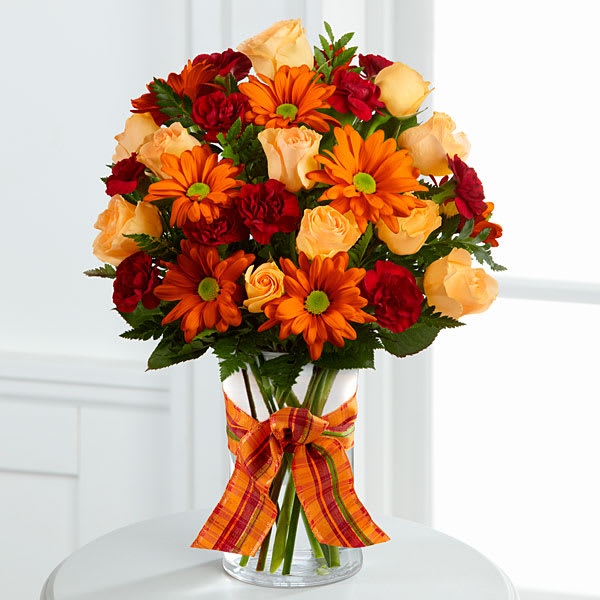 The FTD Golden Autumn Bouquet - The FTD® Golden Autumn™ Bouquet exudes the warmth and comfort of the harvest season with each colorful bloom. Peach spray roses burgundy mini carnations butterscotch chrysanthemums and lush greens are arranged beautifully in a classic clear glass vase accented with an orange plaid ribbon around the neck creating a truly wonderful bouquet that will send your sweetest sentiments to your special recipient for a fantastic fall.