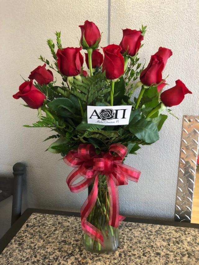 Bouquet of red roses in a clear glass vase with a pink ribbon