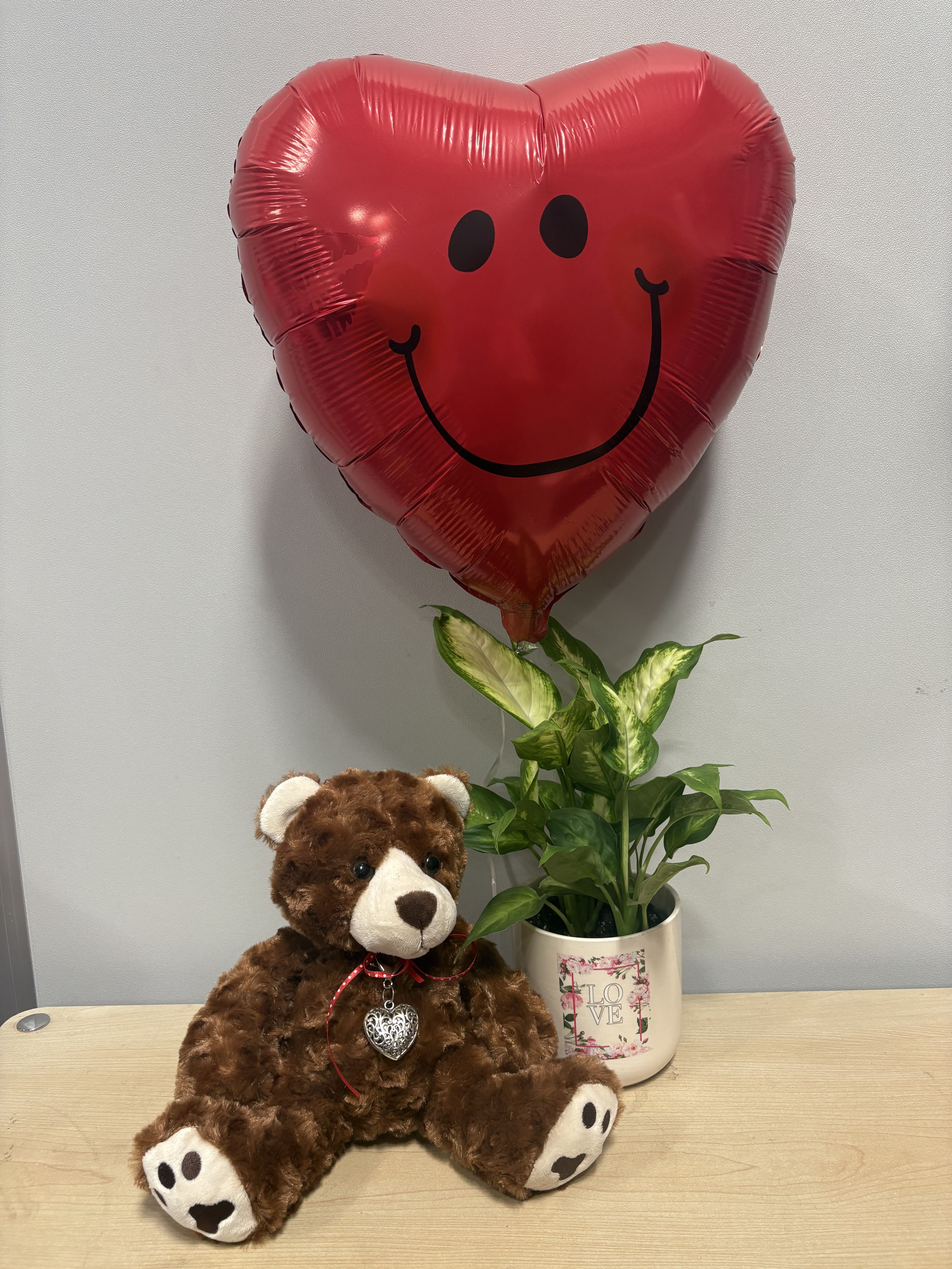 Heart-shaped smiley balloon with a teddy bear and potted plant