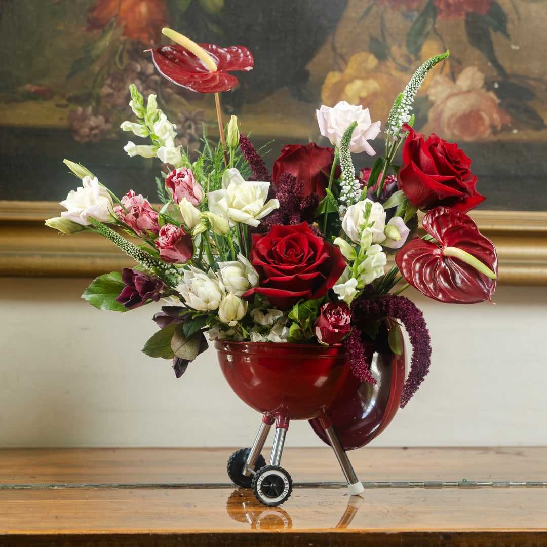 Red and white floral arrangement in a red grill-shaped container