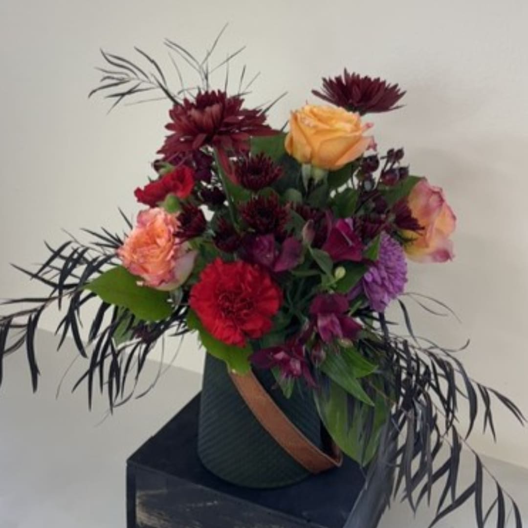 Mixed bouquet with roses and dark purple flowers in a vase