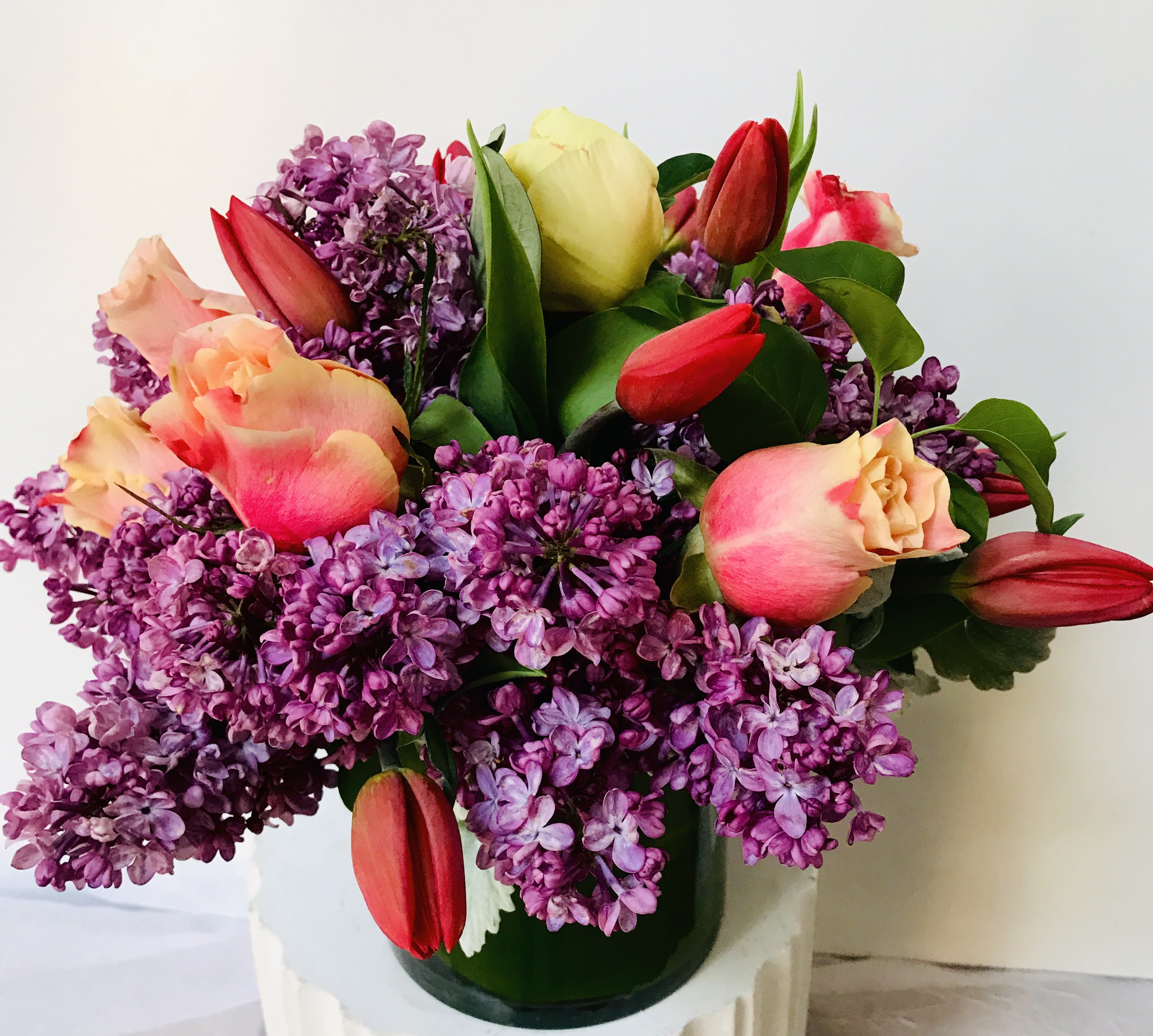 Bouquet of purple lilacs and pink tulips in a glass vase