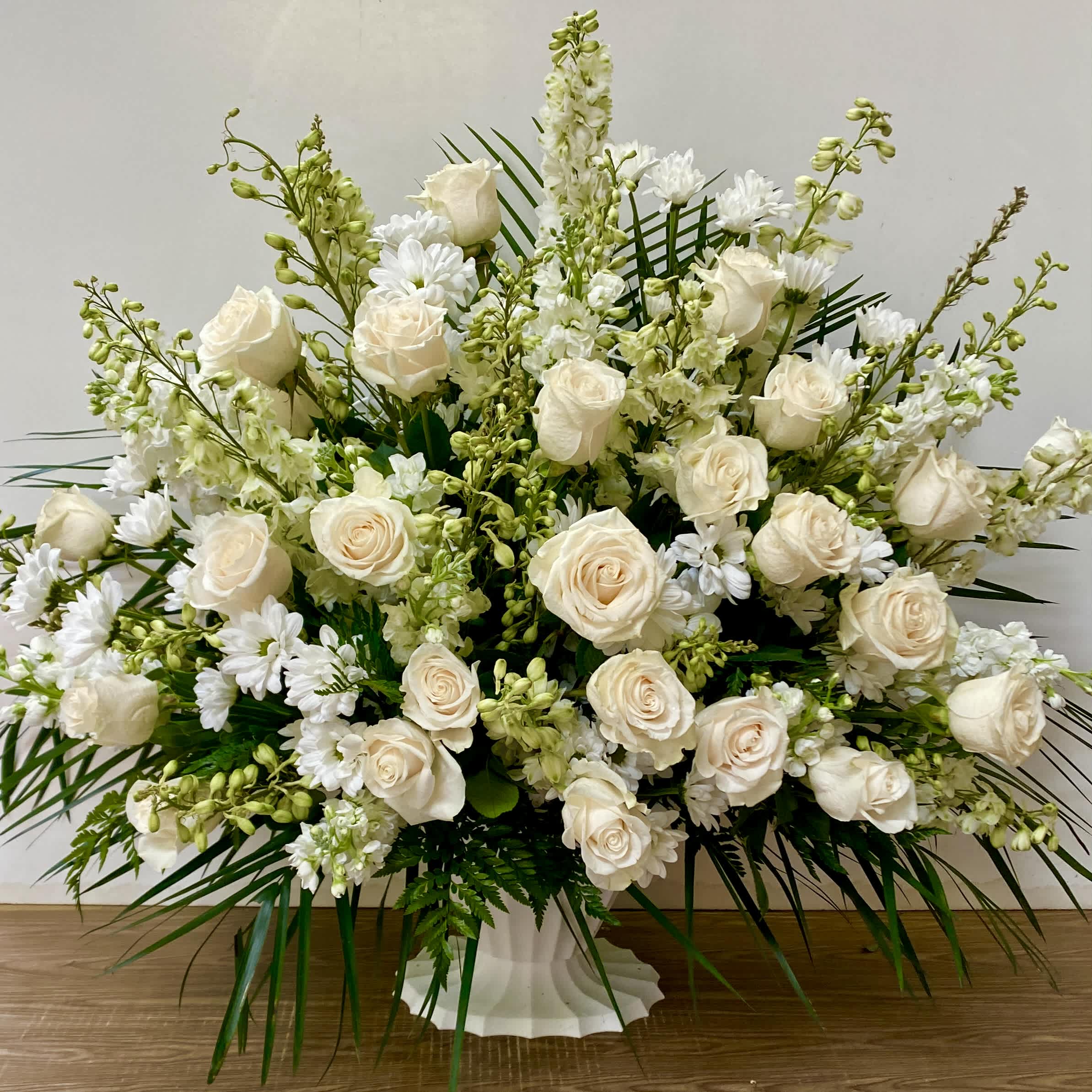 White roses and white daisies in a white pedestal vase