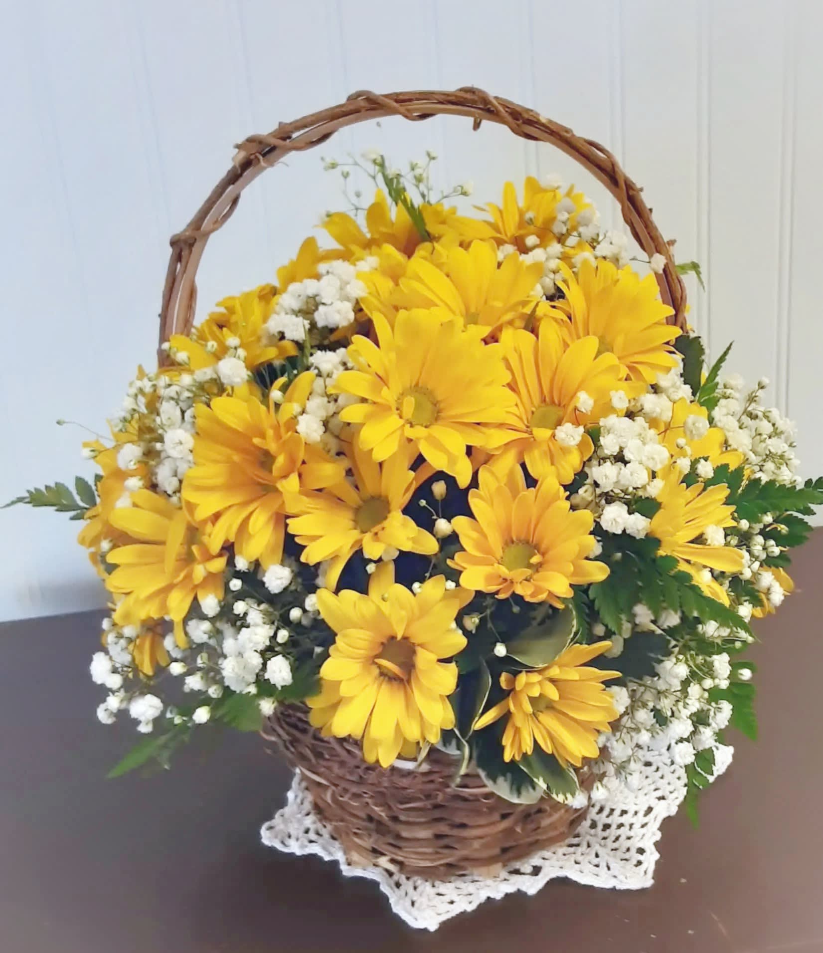 Yellow daisy bouquet in a wicker basket with white filler flowers