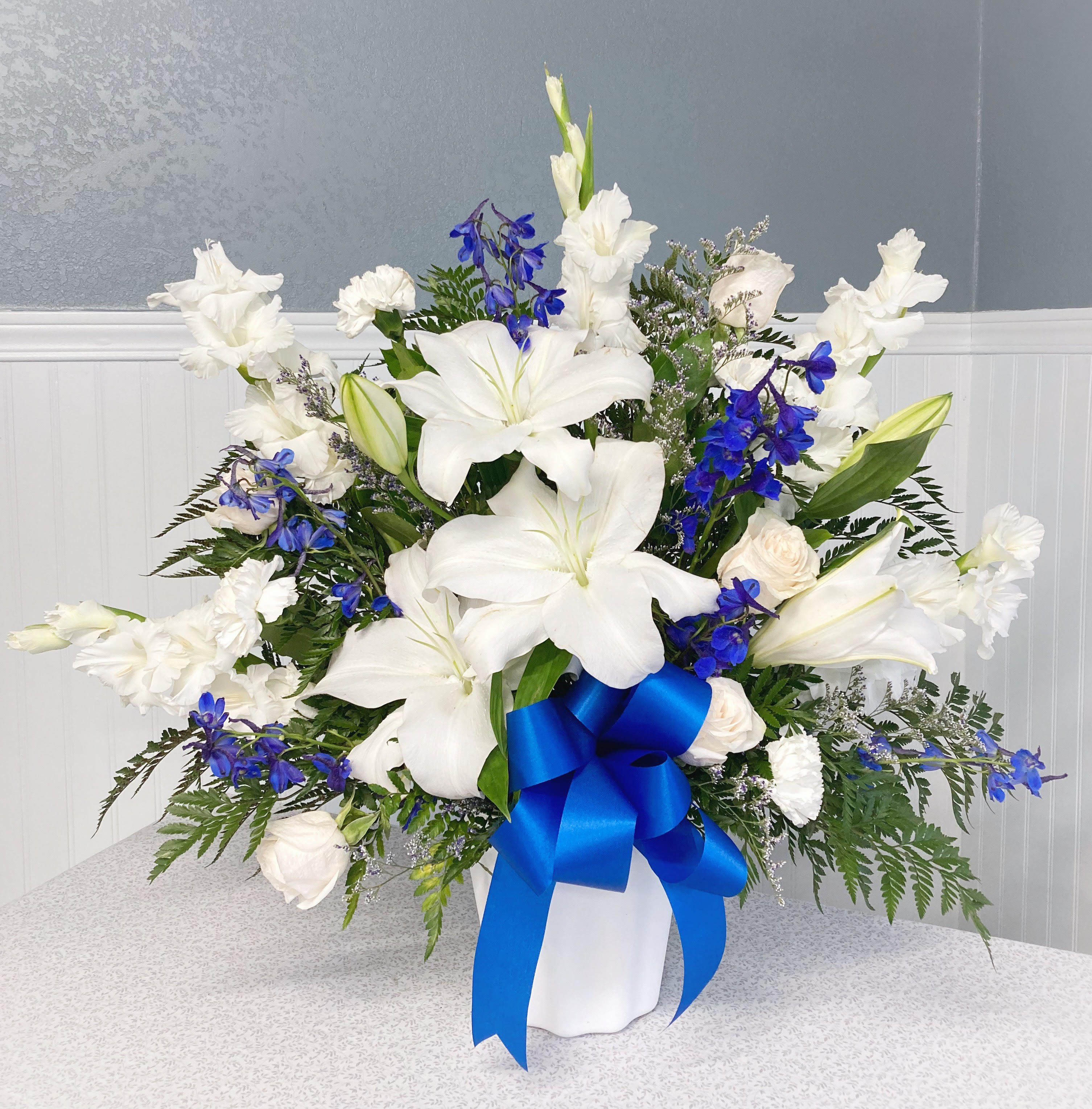 Heartfelt Remembrance Blue and White  - Both simple and undeniably stunning, this standing basket arrangement is a beautiful way for you to convey your deepest sympathies. Delicately crafted by our expert designers. A touching tribute for family, friends, or business associates to send to the services.  Basket arrangement of fresh blue and white flowers. Appropriate for family, friends or business associates to send directly to the funeral home. Our florists use only the freshest flowers available, so colors and varieties may vary. 