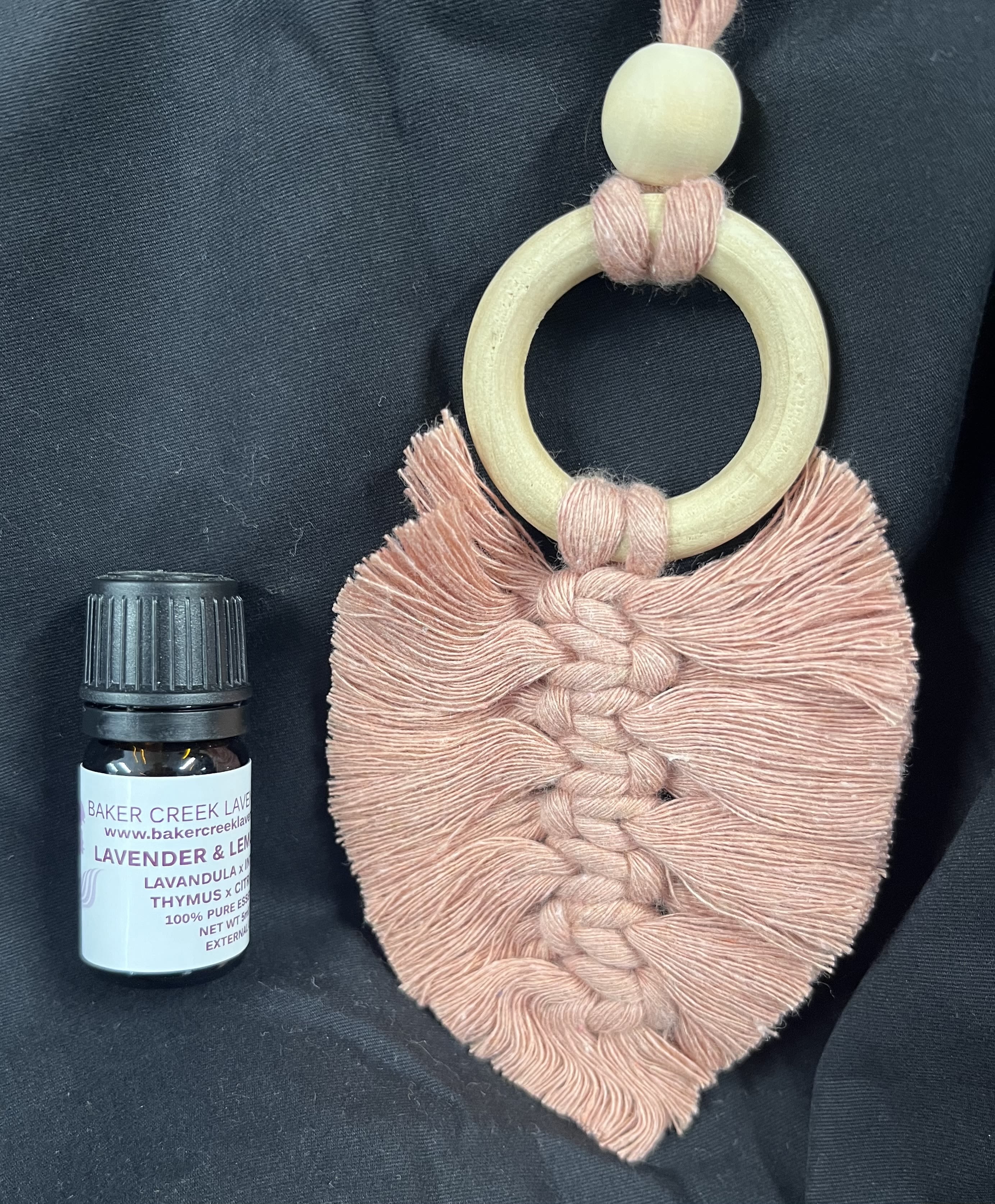 Macrame wall hanging and a small essential oil bottle on dark fabric