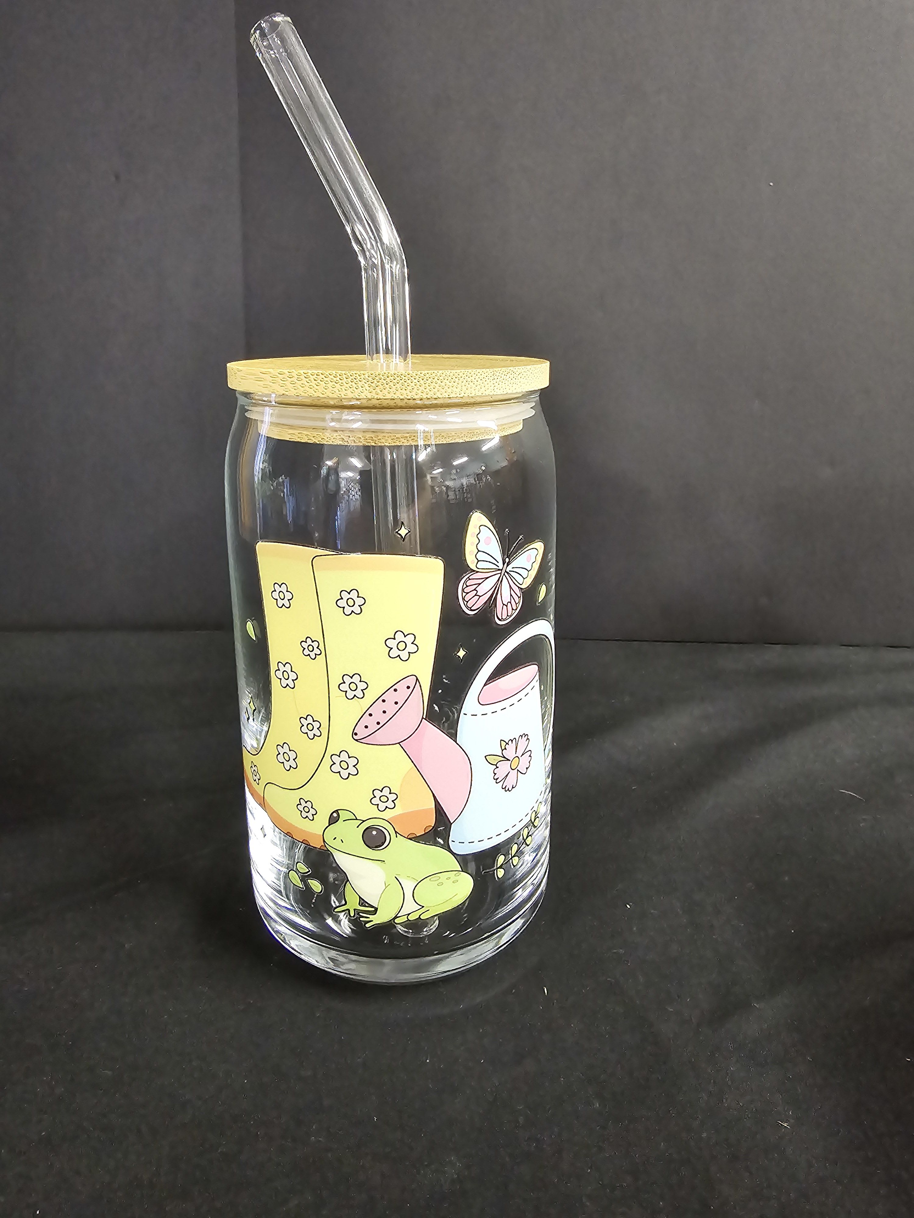 Clear glass tumbler with a bamboo lid and straw, decorated with a frog and butterfly graphic