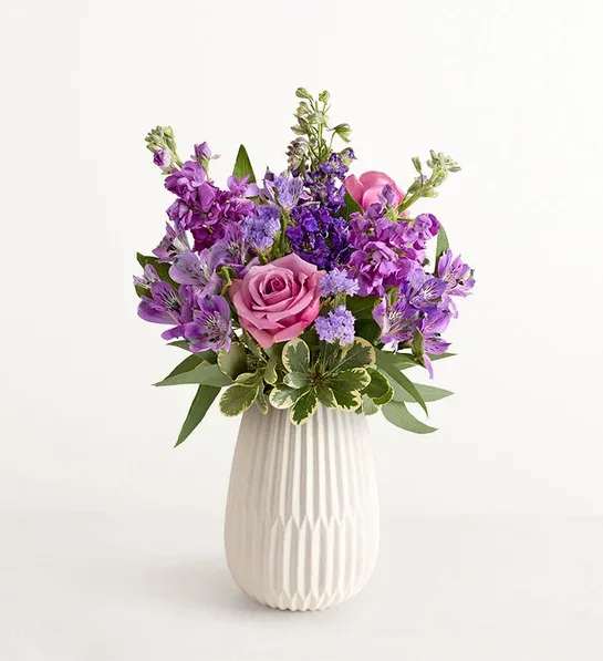 Purple and pink flower arrangement in a white vase