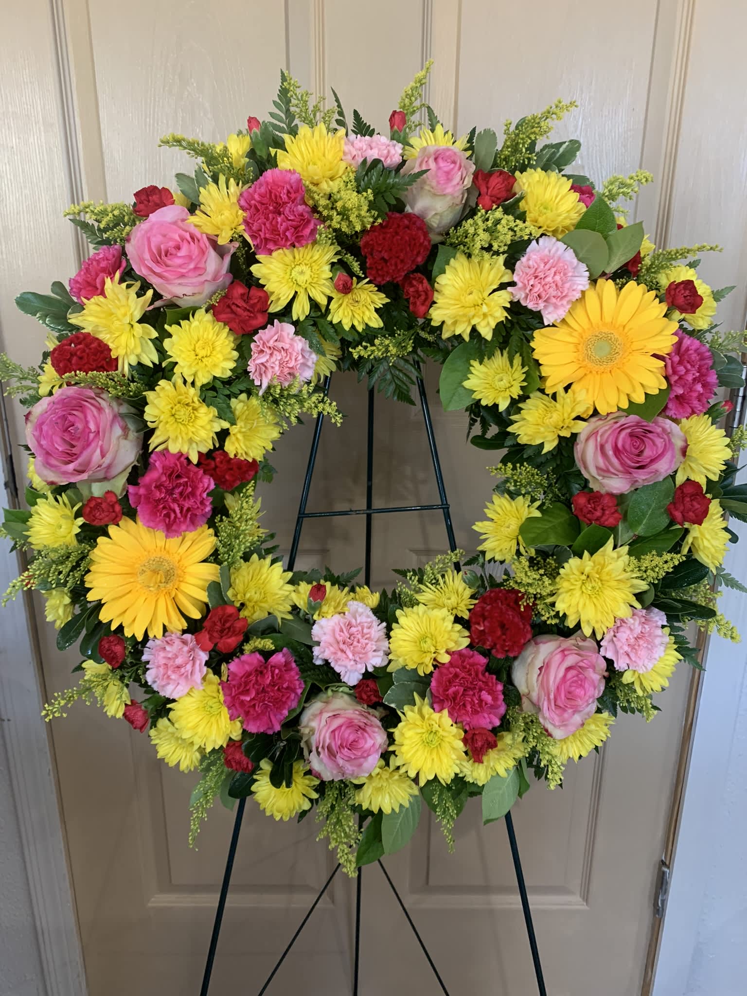 Circular wreath of pink, yellow, and red flowers on a stand