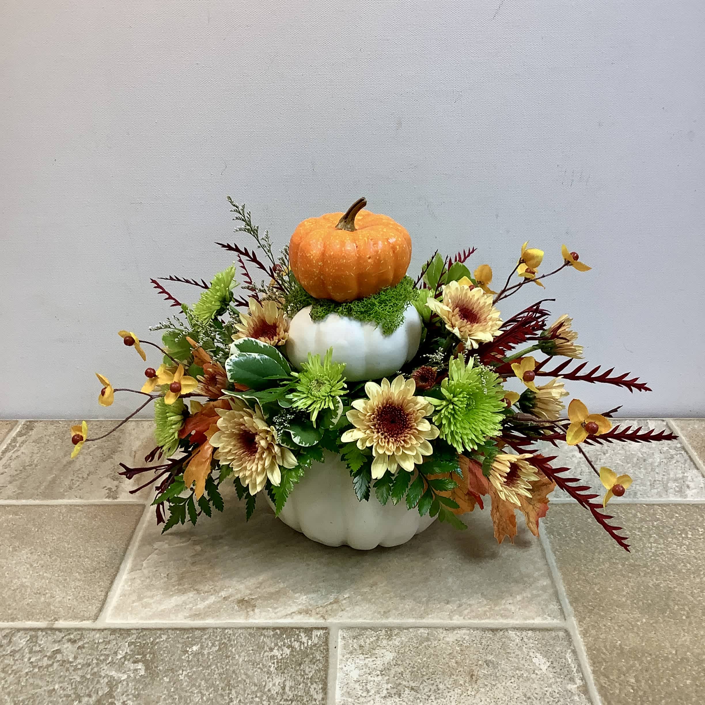 Pumpkin centerpiece with yellow flowers in stacked white containers