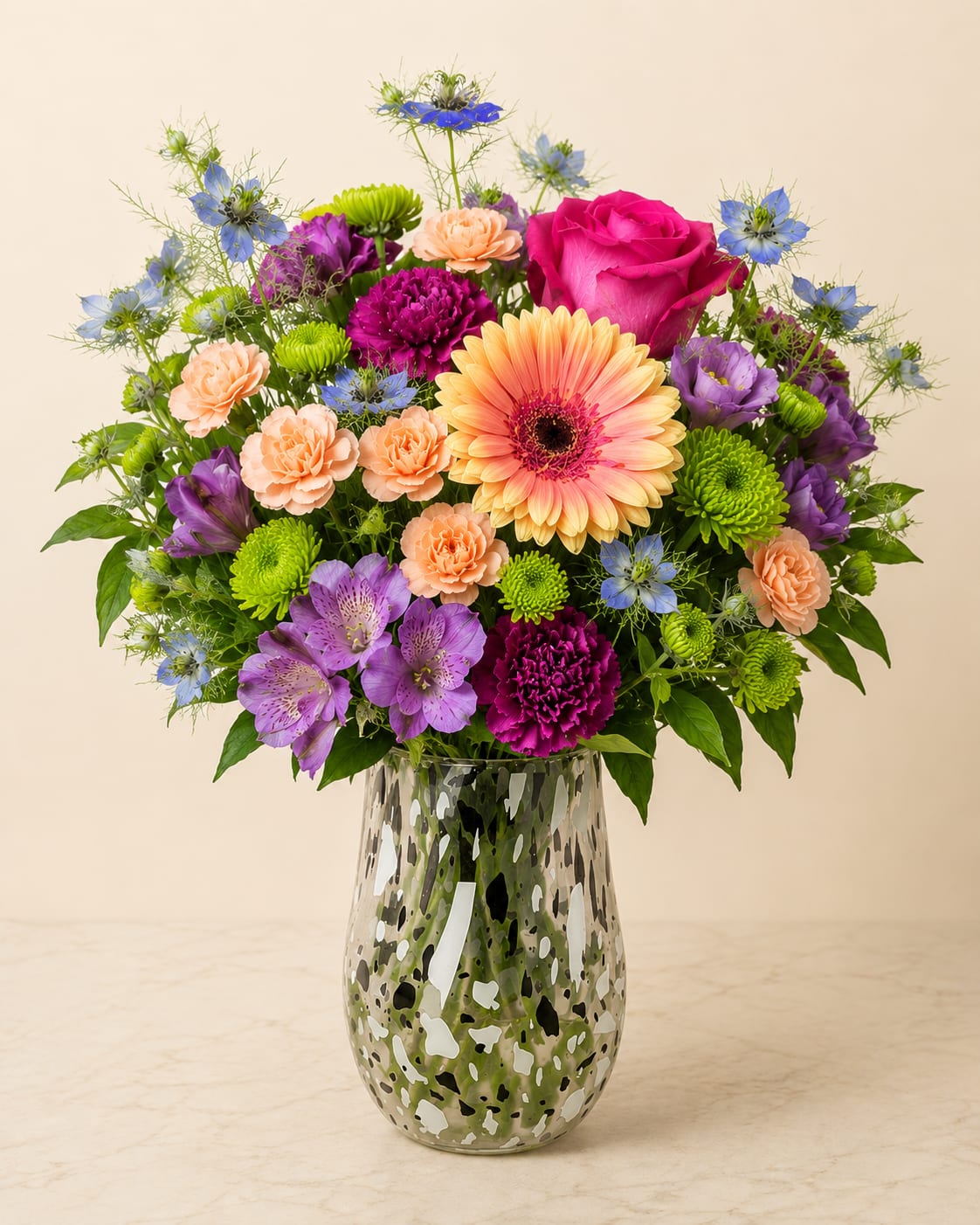 Garden Vase Arrangement - Soft, fresh, and effortlessly, this arrangement features a beautiful blend of colorful blooms arranged in a textured glass vase.   The mix of textures and bright tones brings a calming, sophisticated feel—perfect for celebrations, or simply brightening a space. The clear patterned vase adds a subtle touch of charm while allowing the natural beauty of each stem to shine.  Handcrafted with care, every arrangement is uniquely designed to feel balanced, fresh, and naturally beautiful. Flowers substitutions may happen due to availability.