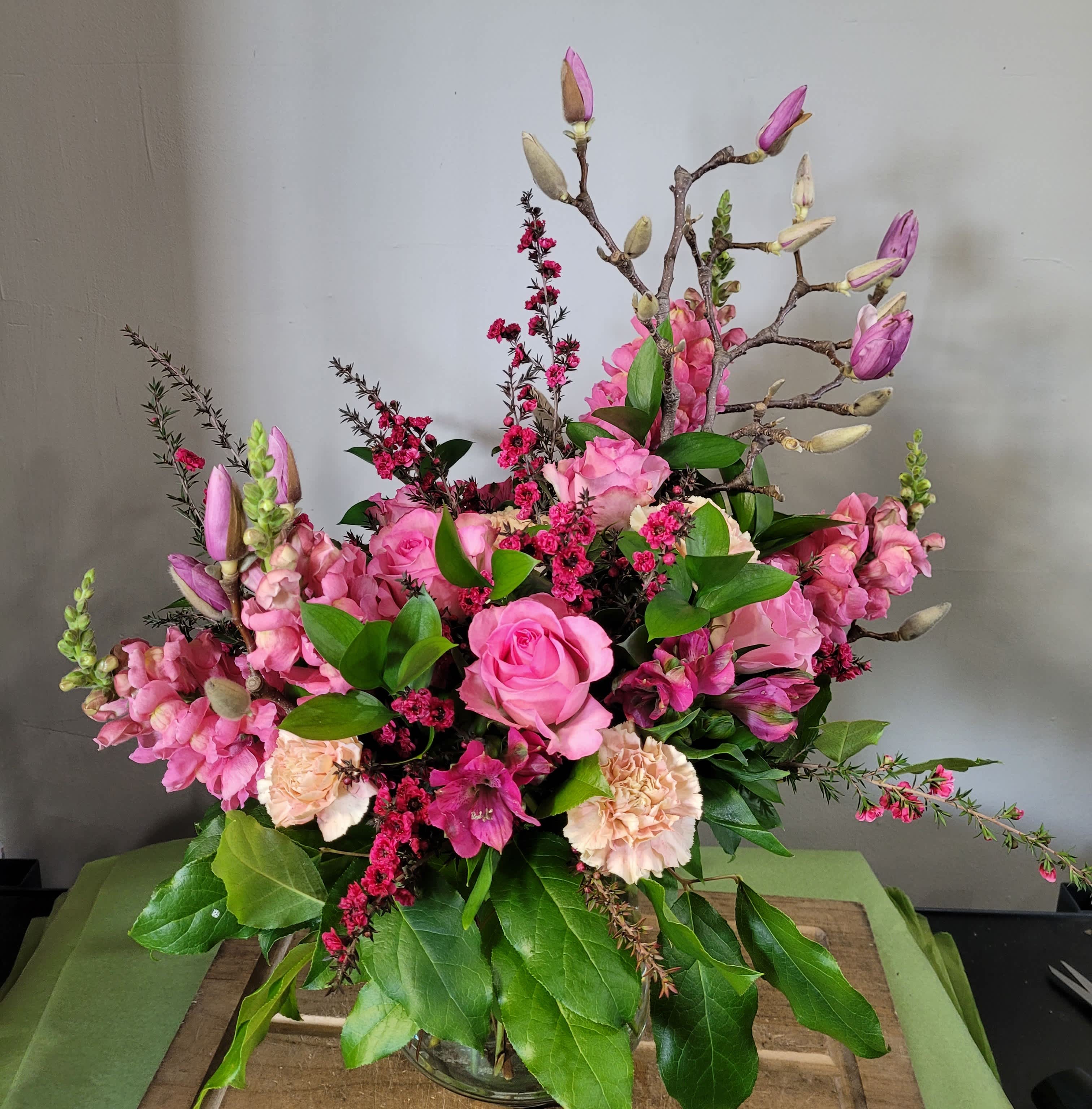 Tall pink rose and snapdragon arrangement with peach carnations in a clear glass vase
