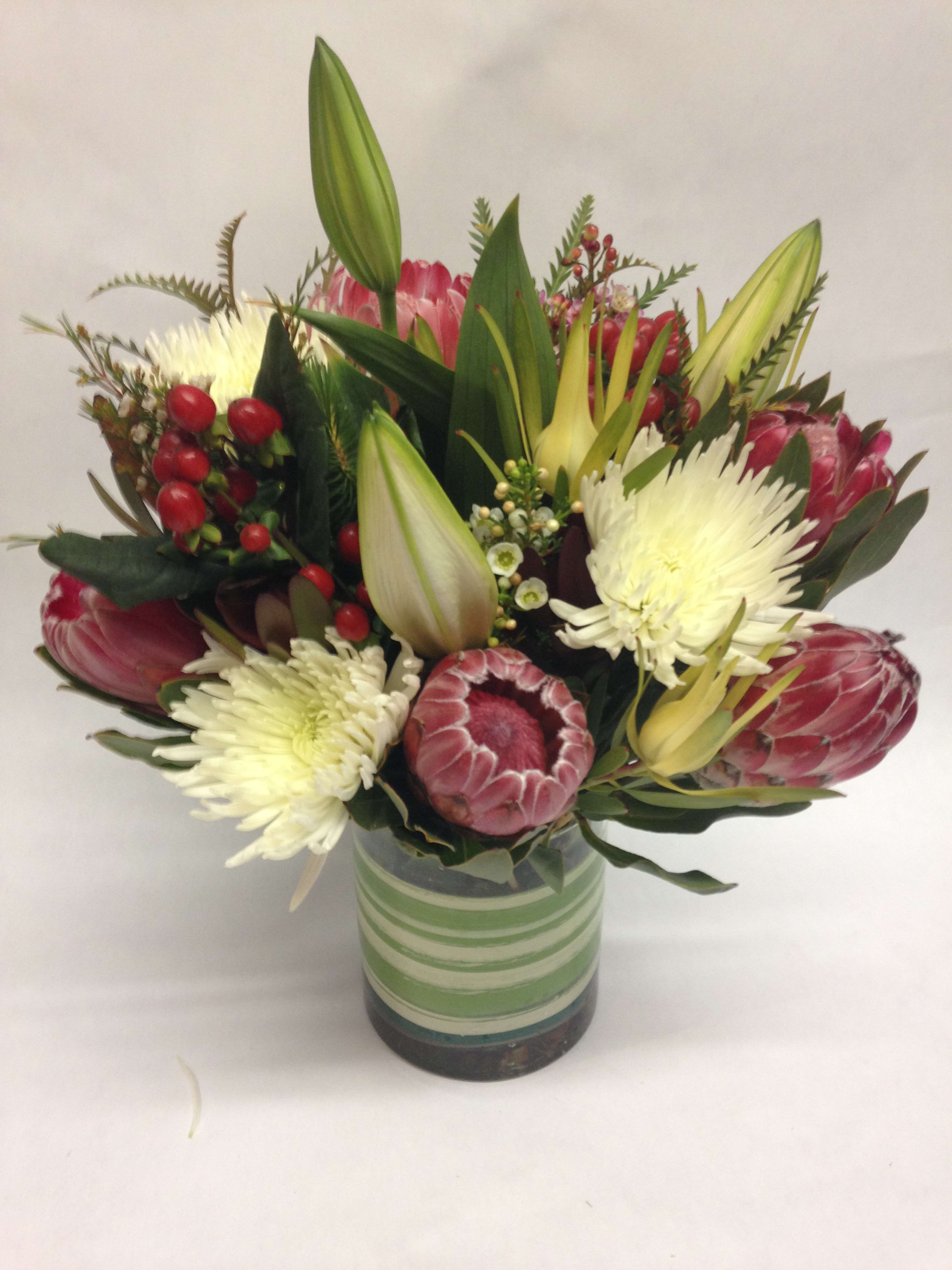 Bouquet of pink protea and white chrysanthemums in a striped glass vase