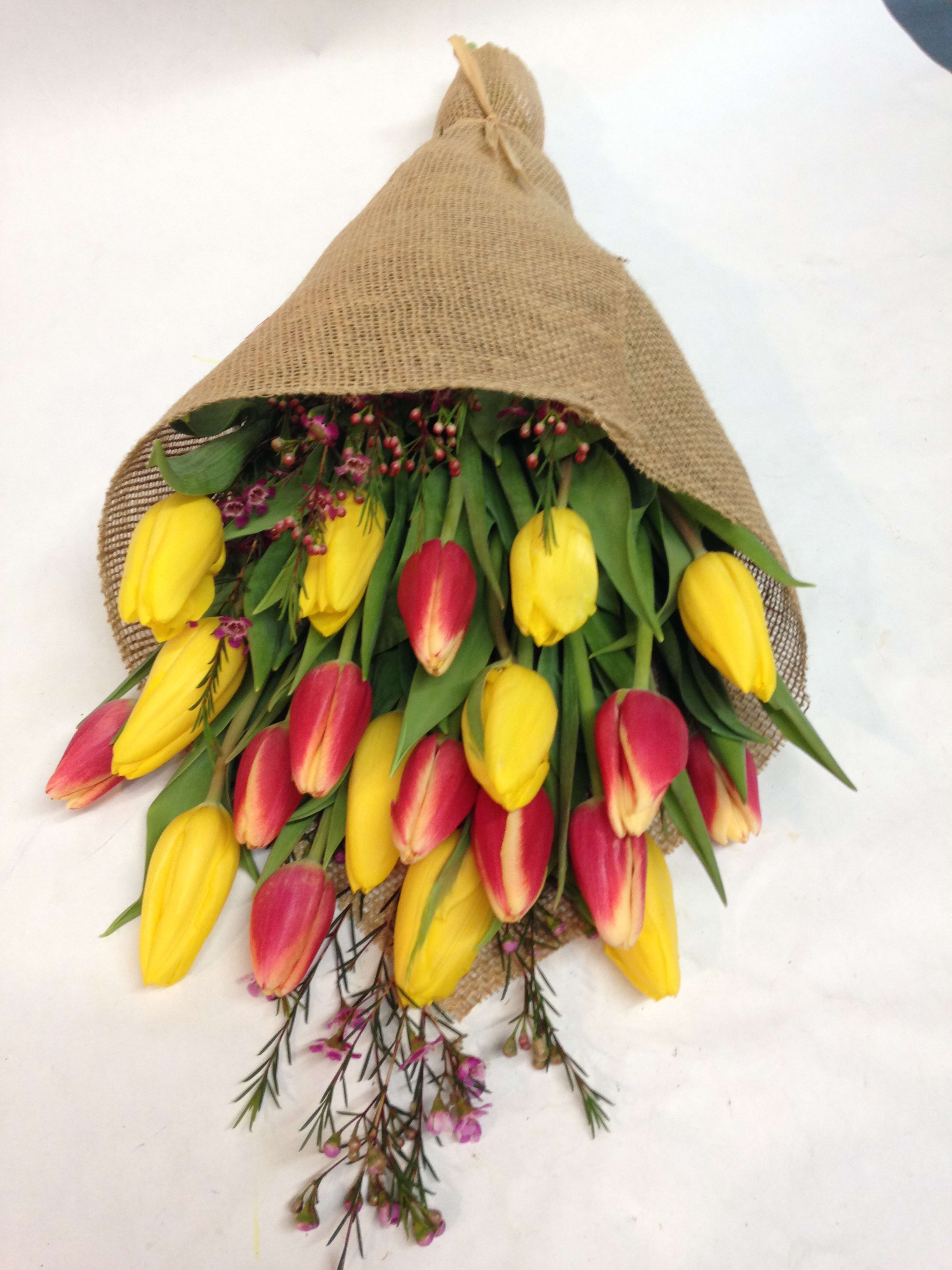 Bouquet of yellow and pink tulips wrapped in burlap