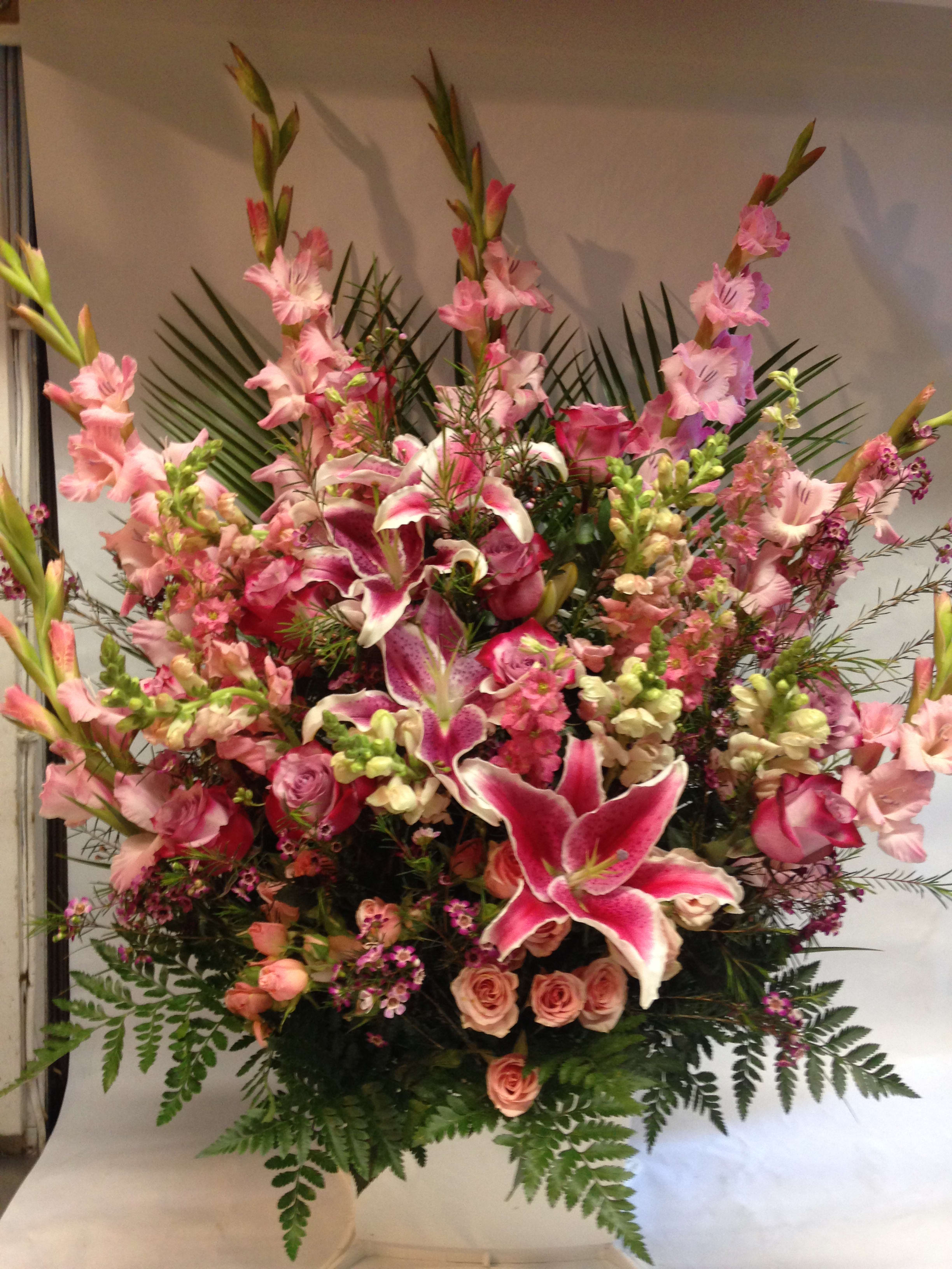 Large pink floral arrangement with lilies, roses, and tall gladiolus