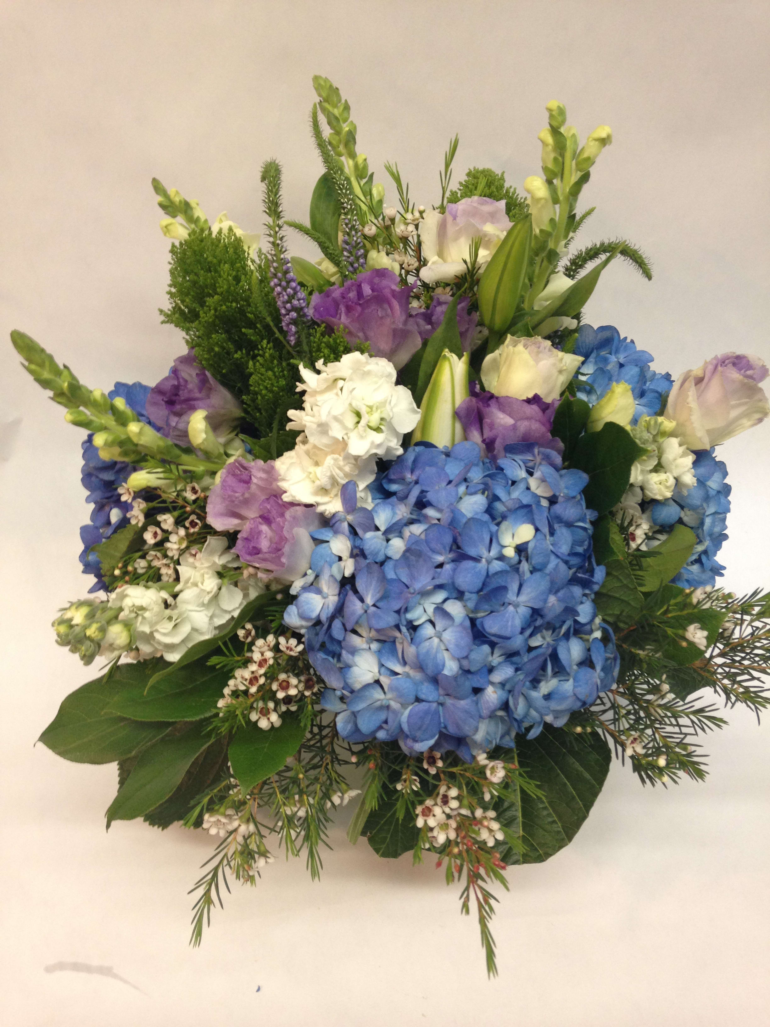 Bouquet of blue hydrangeas, purple blooms, and white flowers