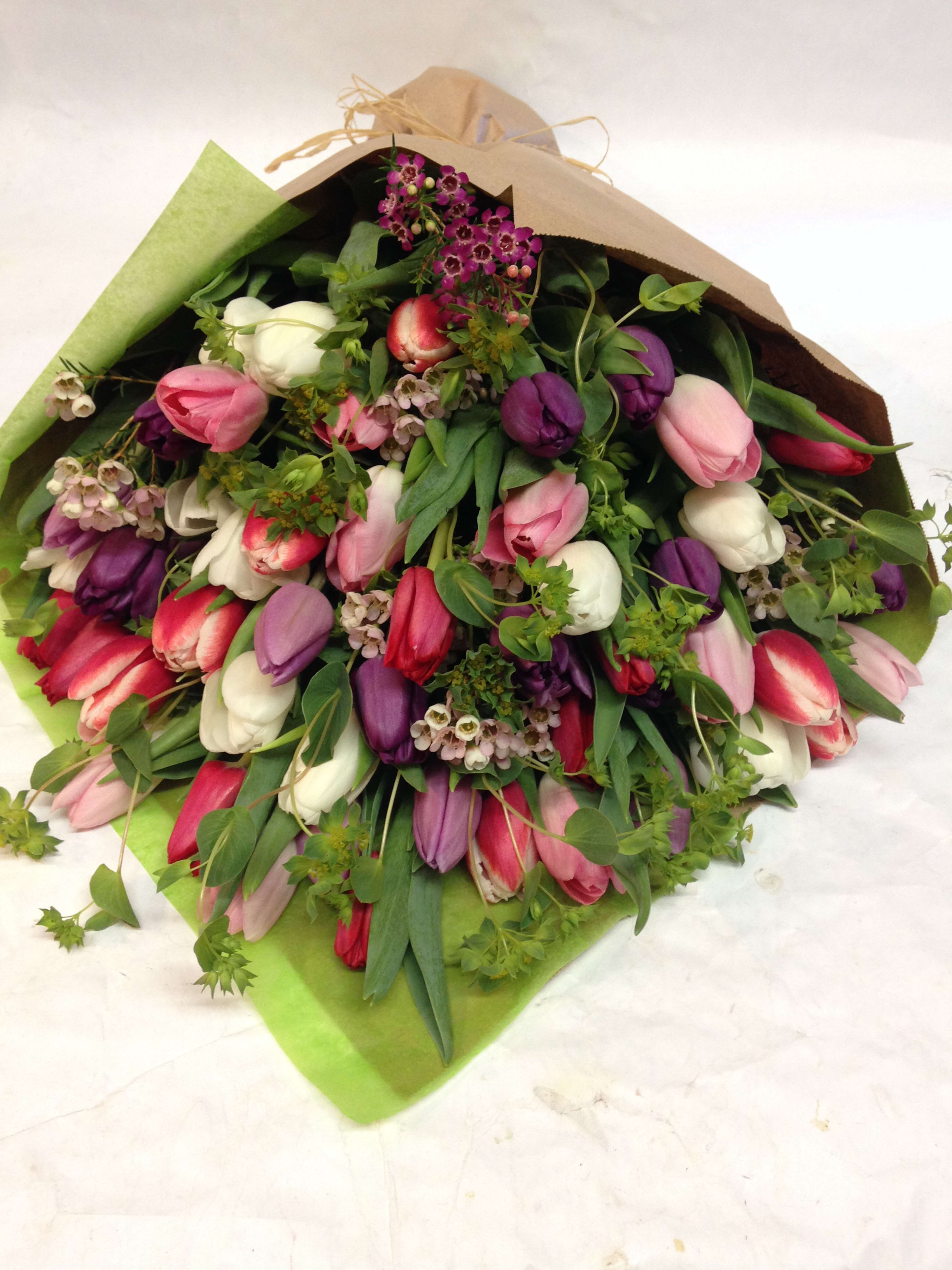 Bouquet of pink, purple, and white tulips wrapped in paper