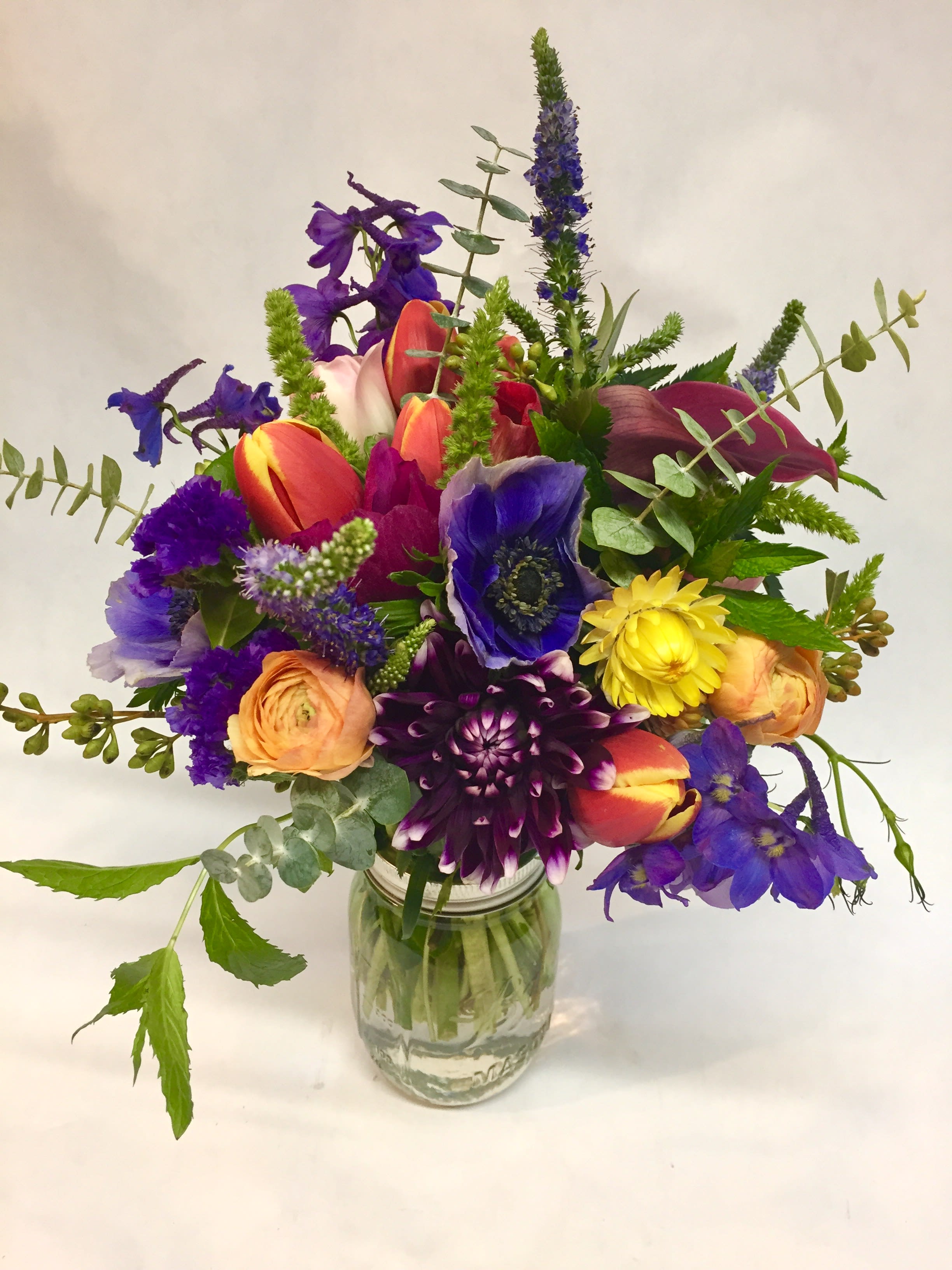 Colorful mixed bouquet in a clear glass jar vase