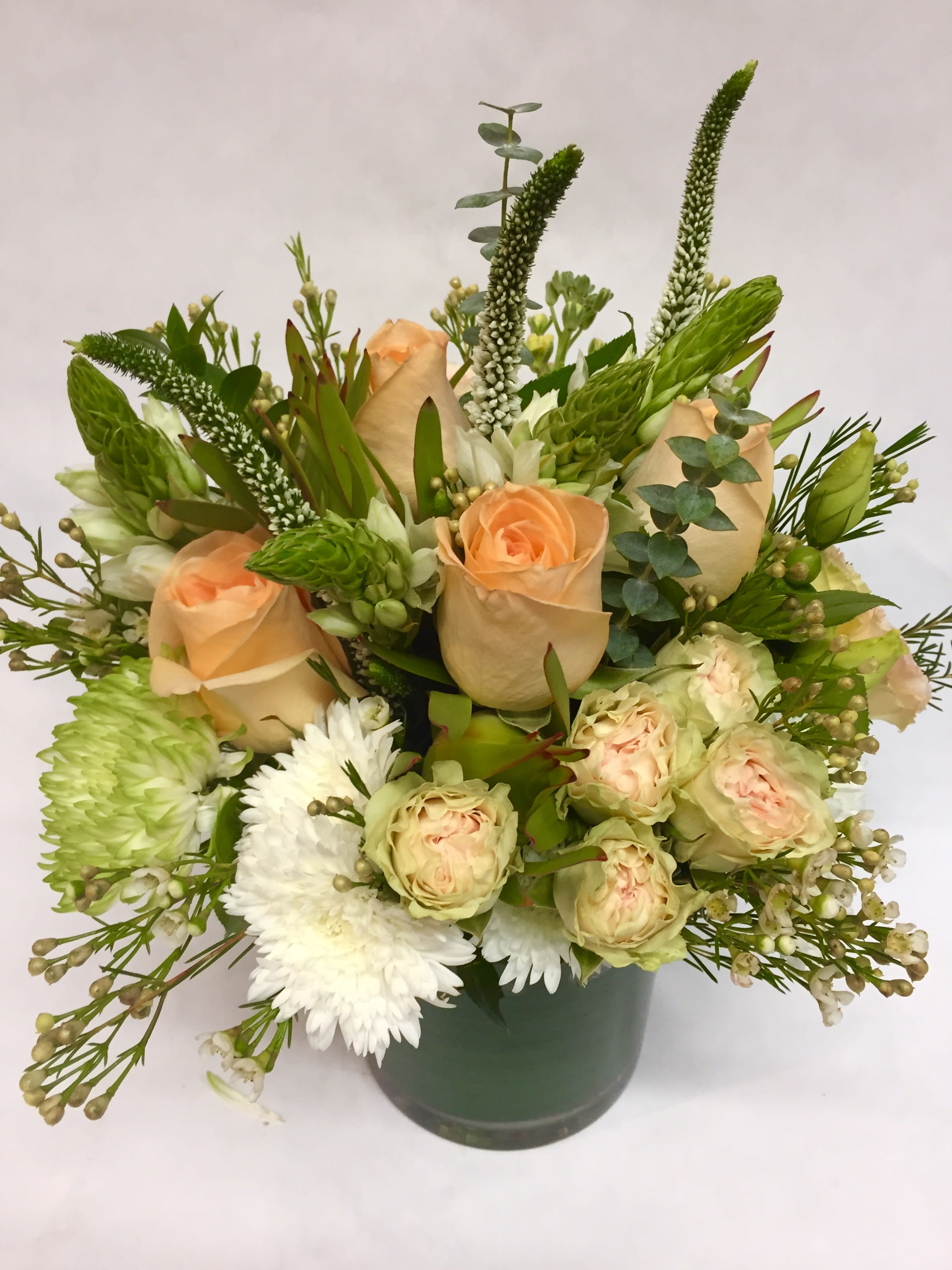 Peach roses and white flowers in a green vase