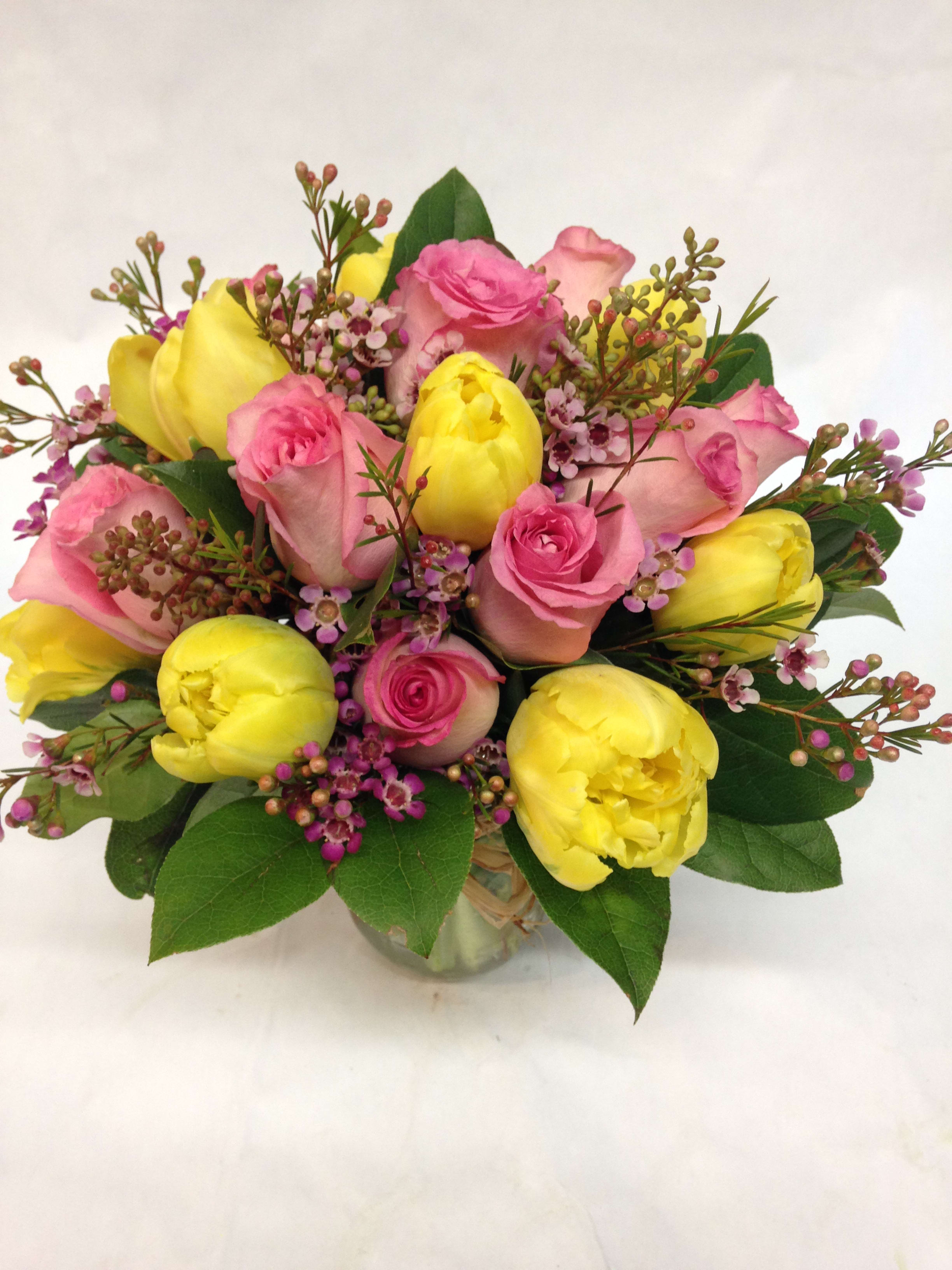 Bouquet of pink roses and yellow tulips in a glass vase