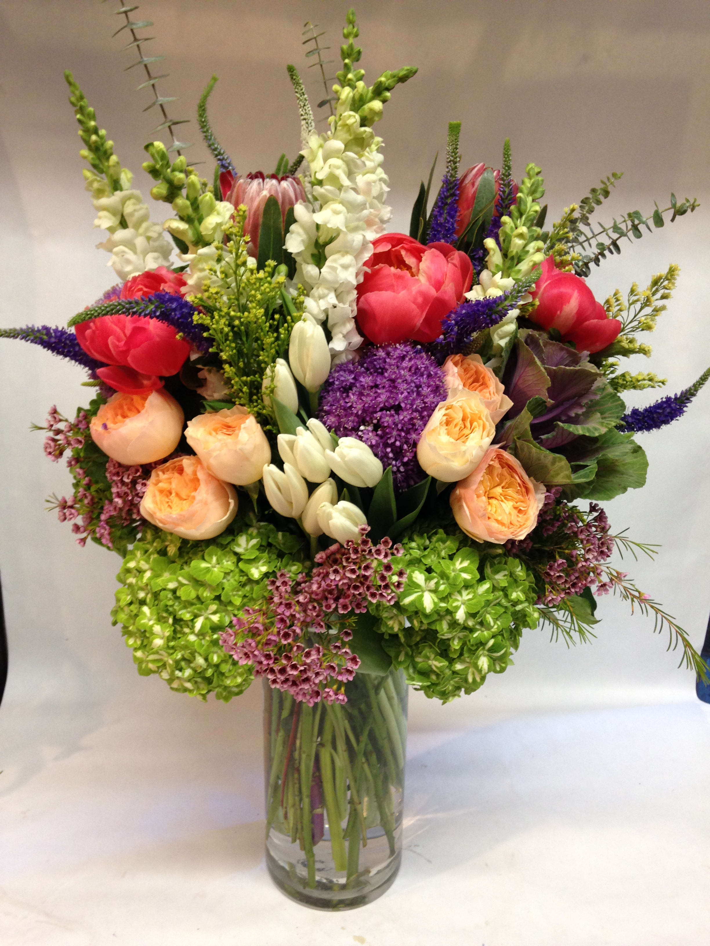 Mixed bouquet in a clear glass vase with pink, peach, white, and purple flowers