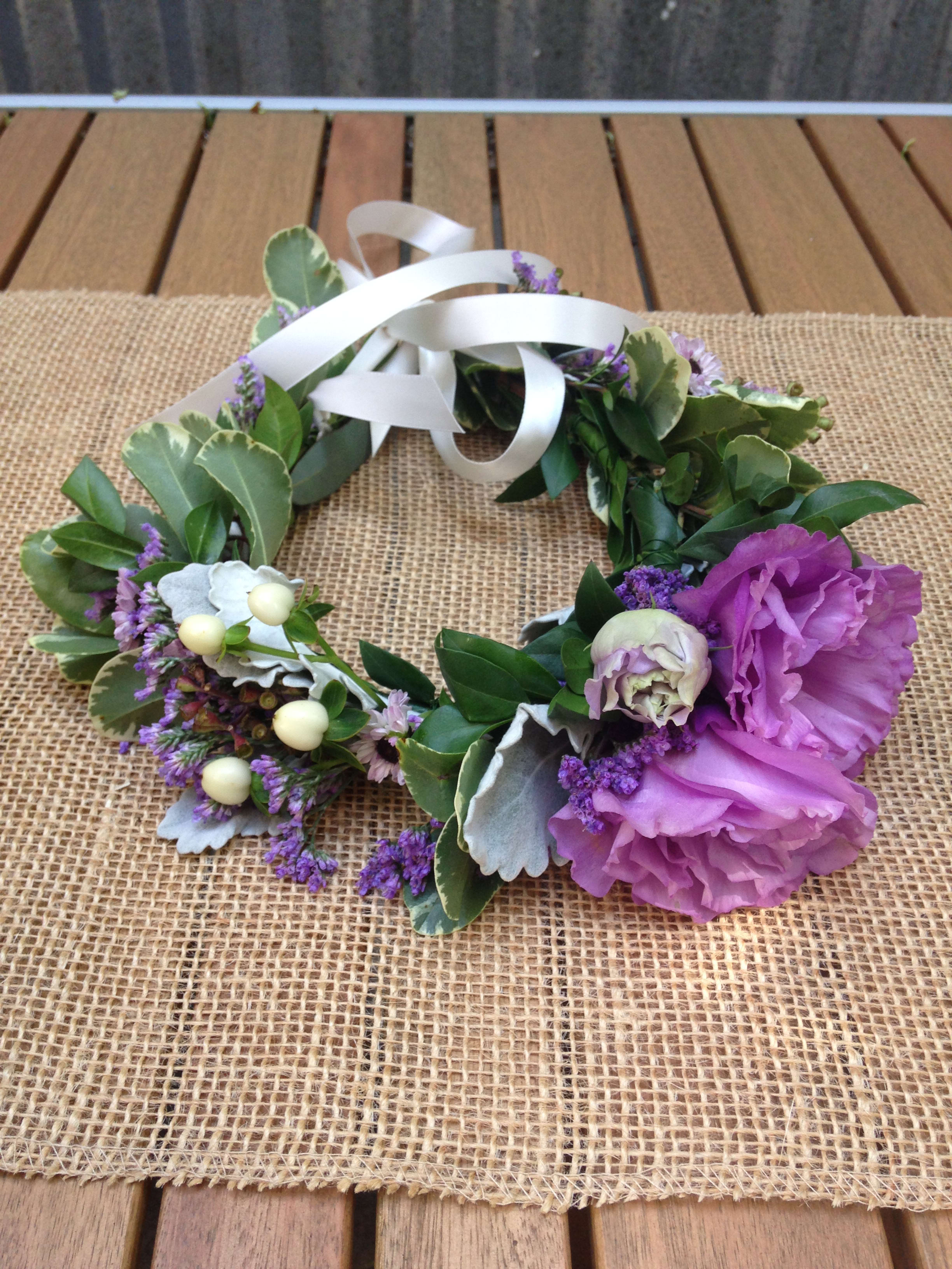Floral wreath with purple blooms and white ribbon on burlap