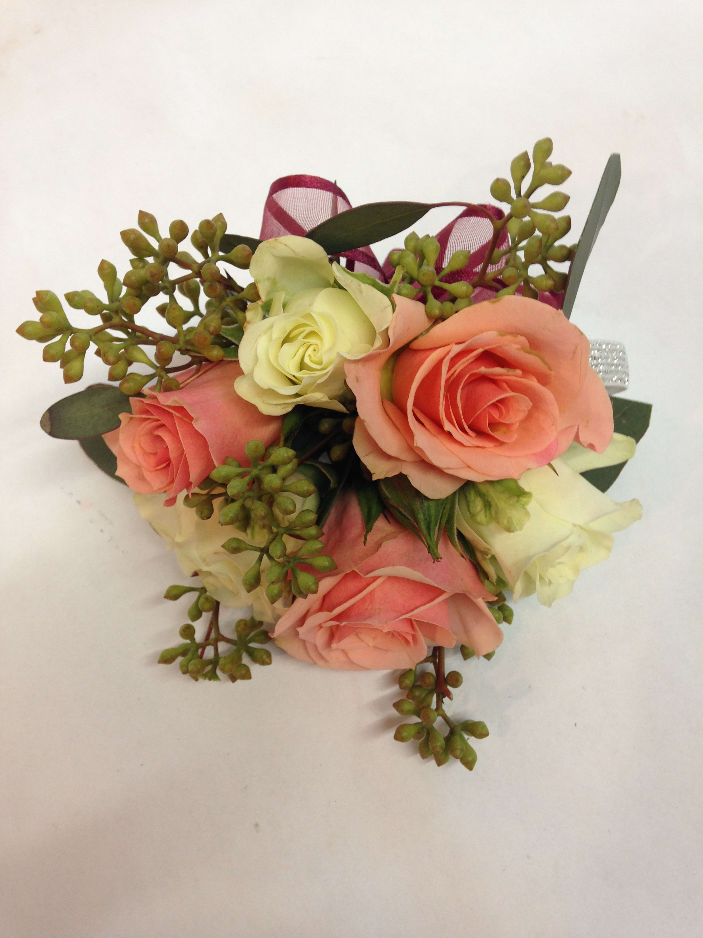 Small bouquet of peach and cream roses with green berries