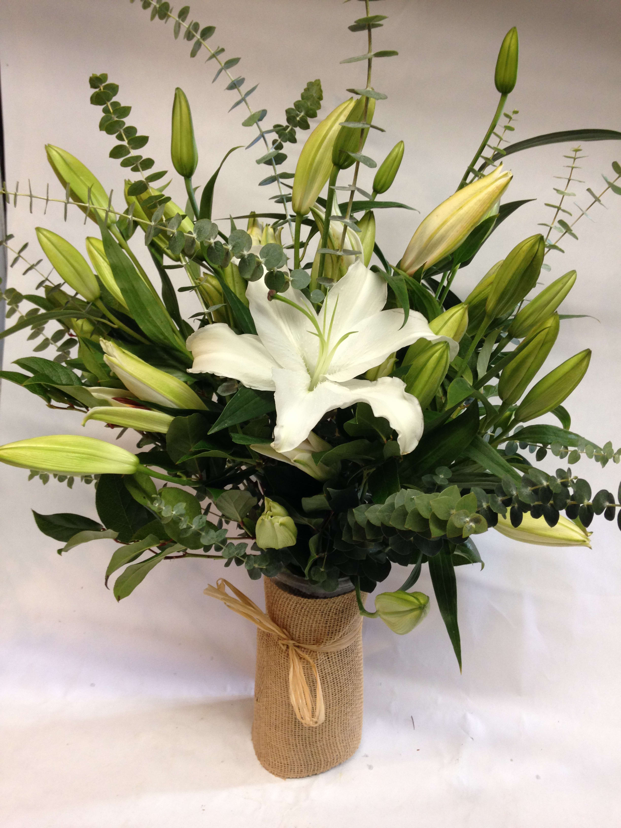 White lily bouquet in a burlap-wrapped vase