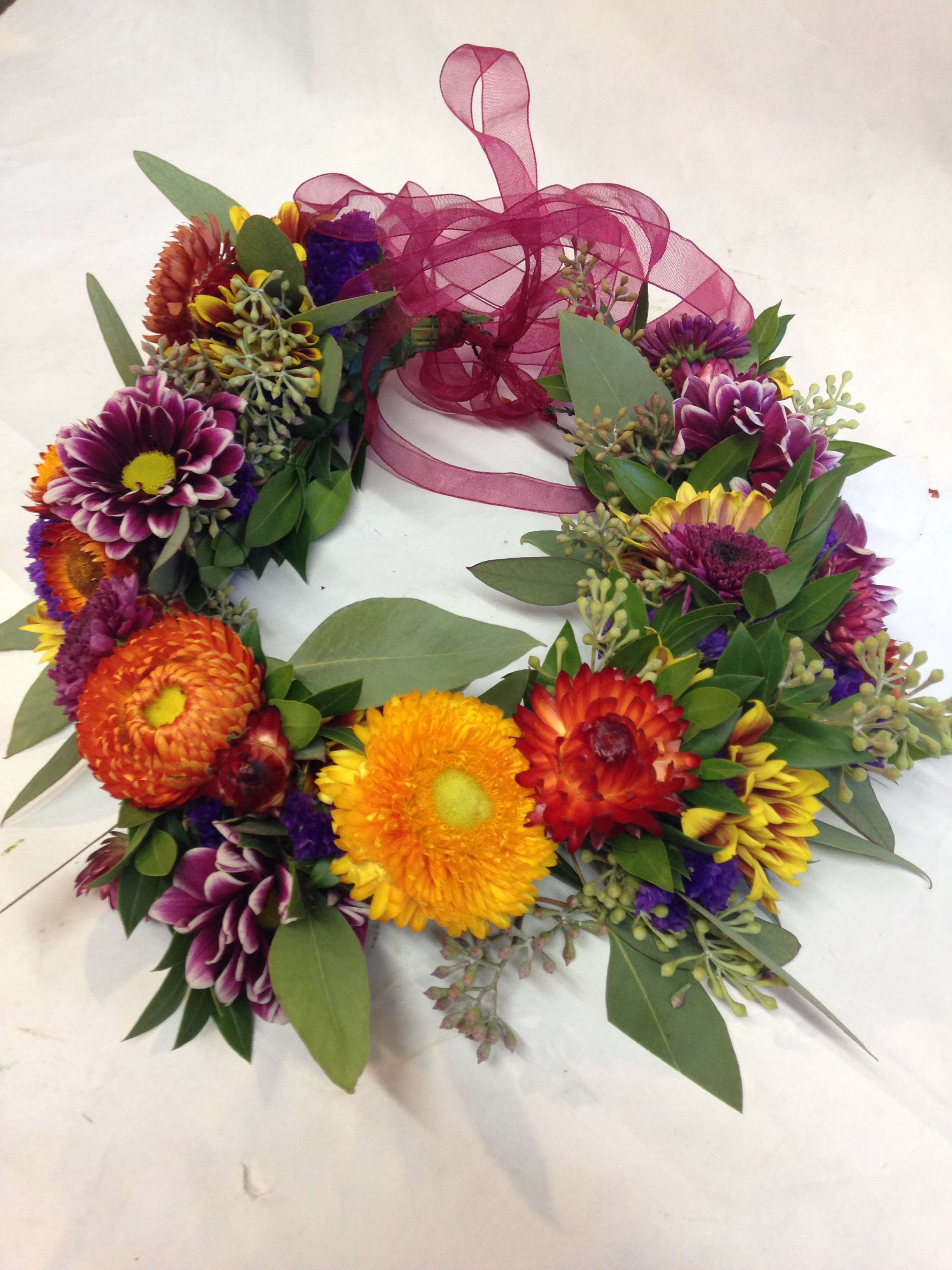 Colorful flower wreath with a magenta ribbon bow