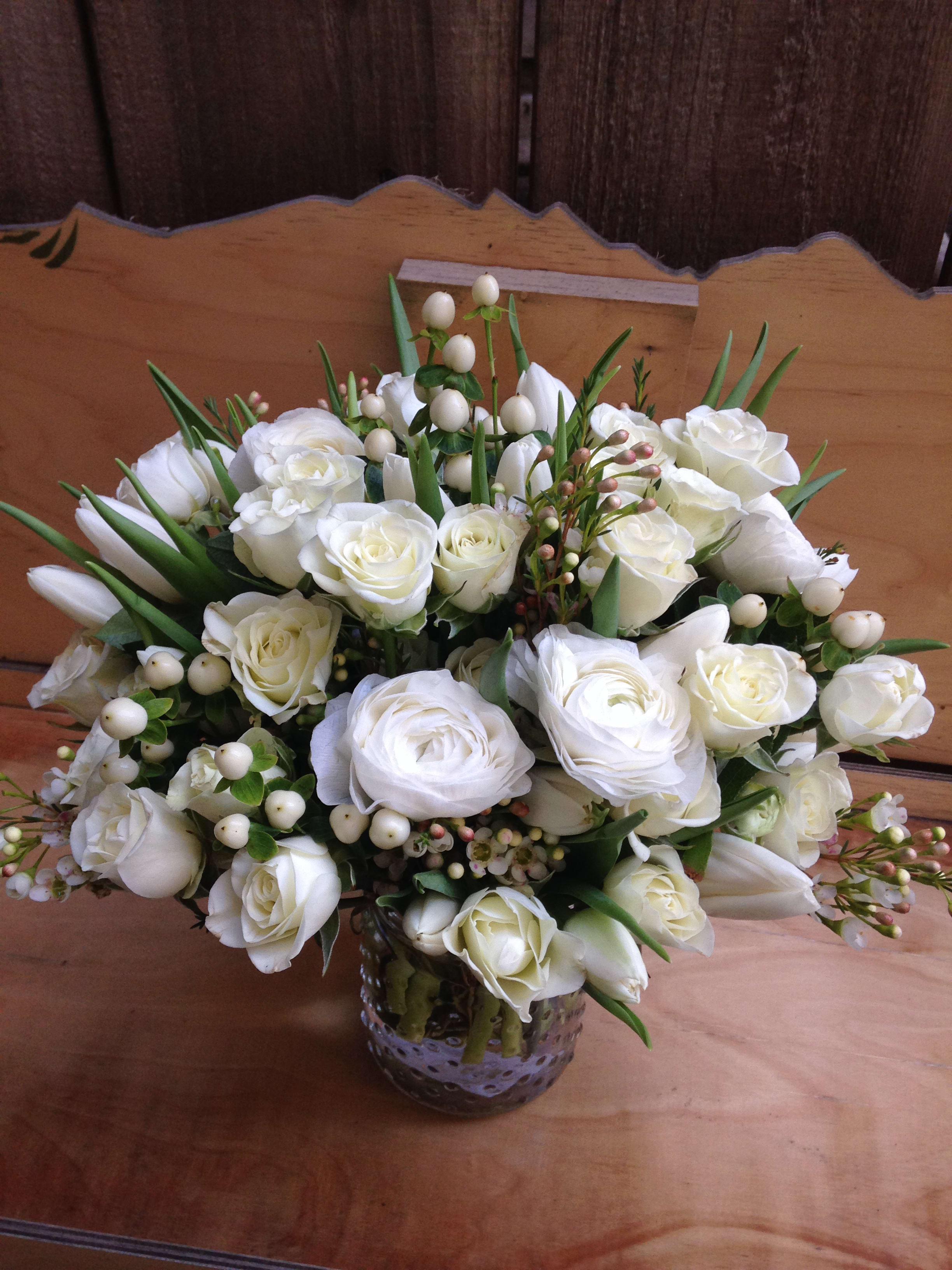 White rose bouquet in a glass vase with berry accents