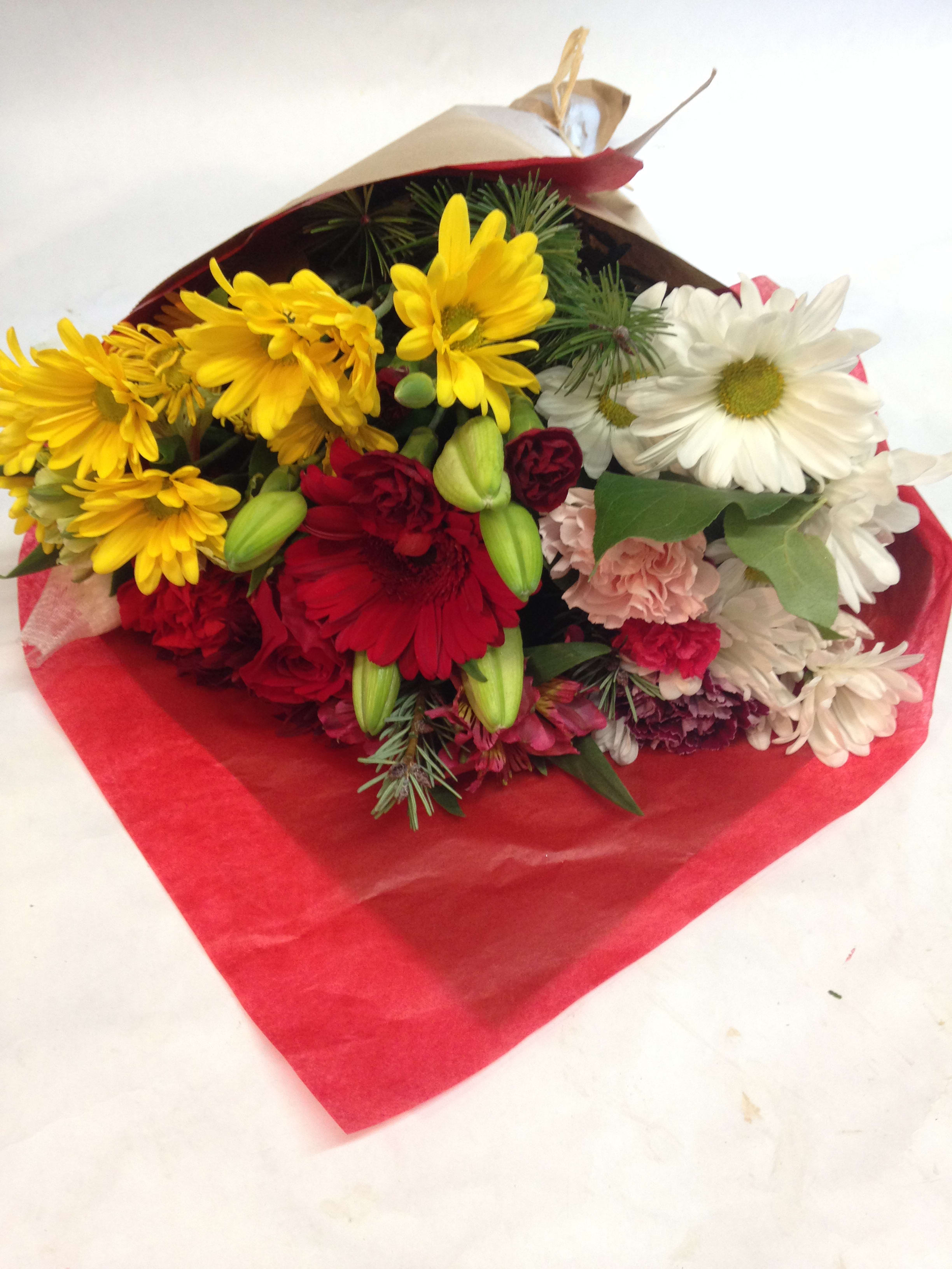 Bouquet of yellow, red, and white daisies wrapped in red paper
