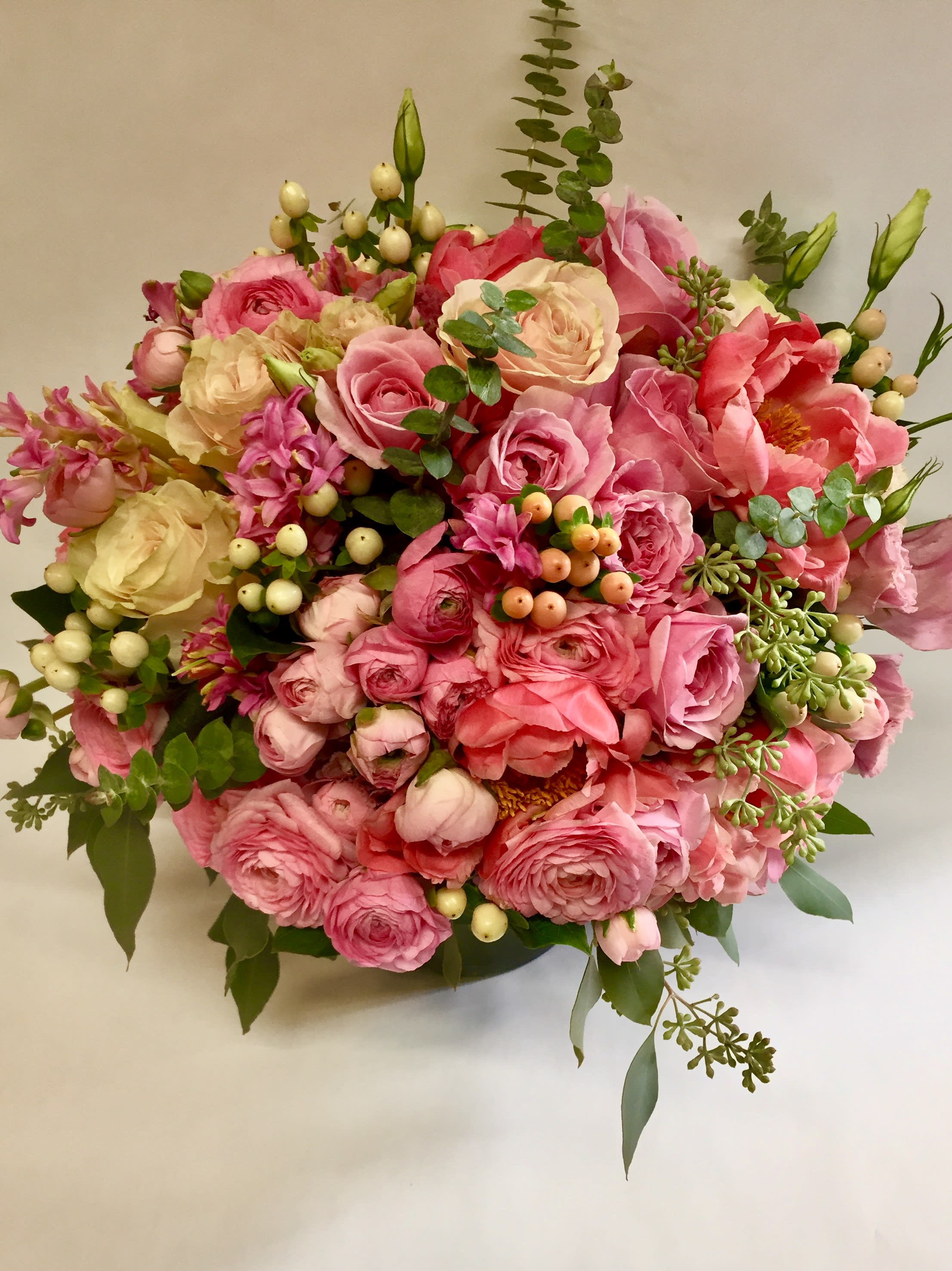 Round bouquet of pink and cream flowers with berries and greenery