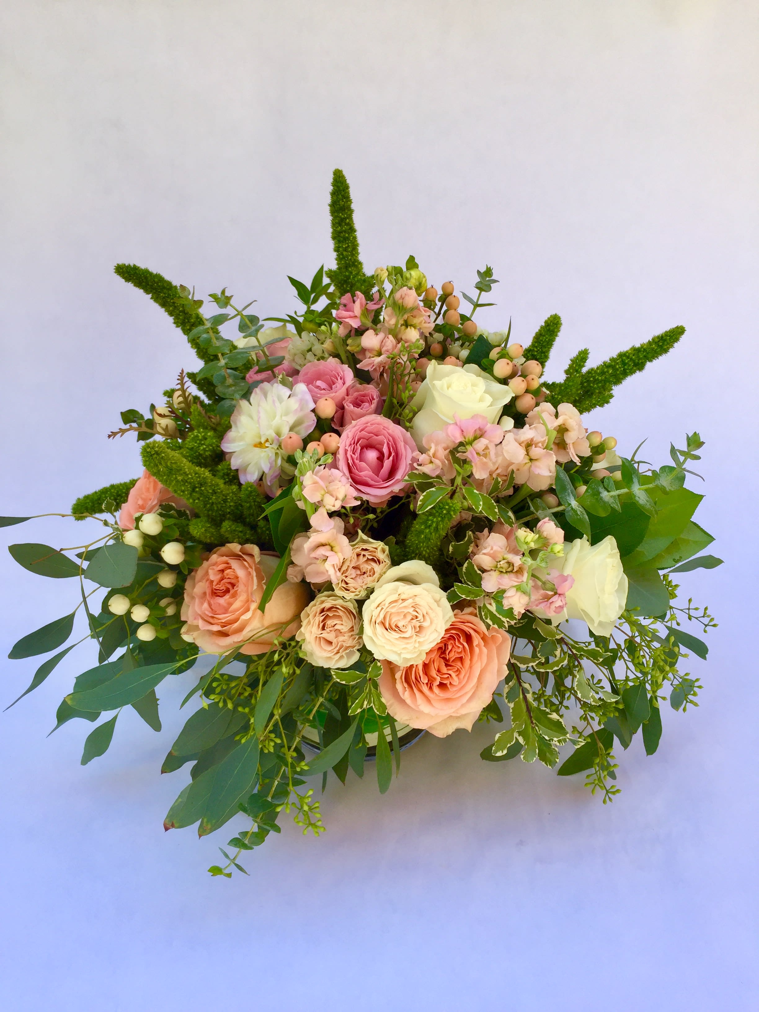 Bouquet of pink and cream roses with greenery and berry accents