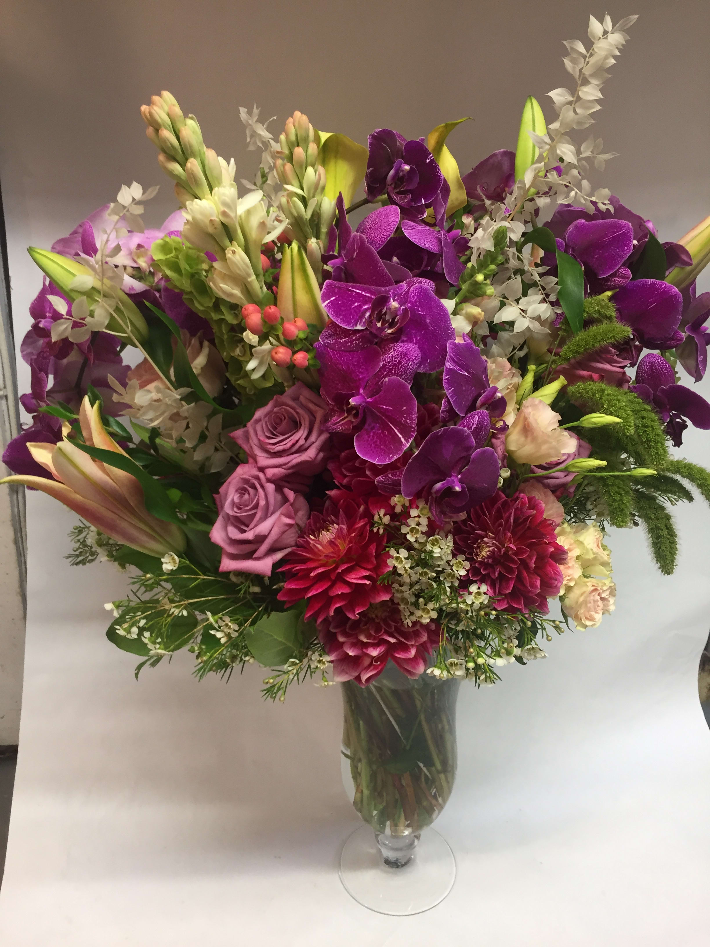 Purple orchid and rose bouquet in a clear glass vase