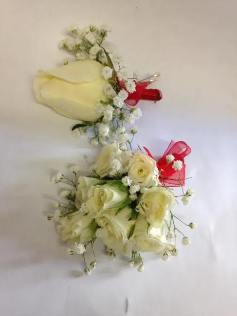 Two ivory rose bouquets with baby's breath and red ribbon accents