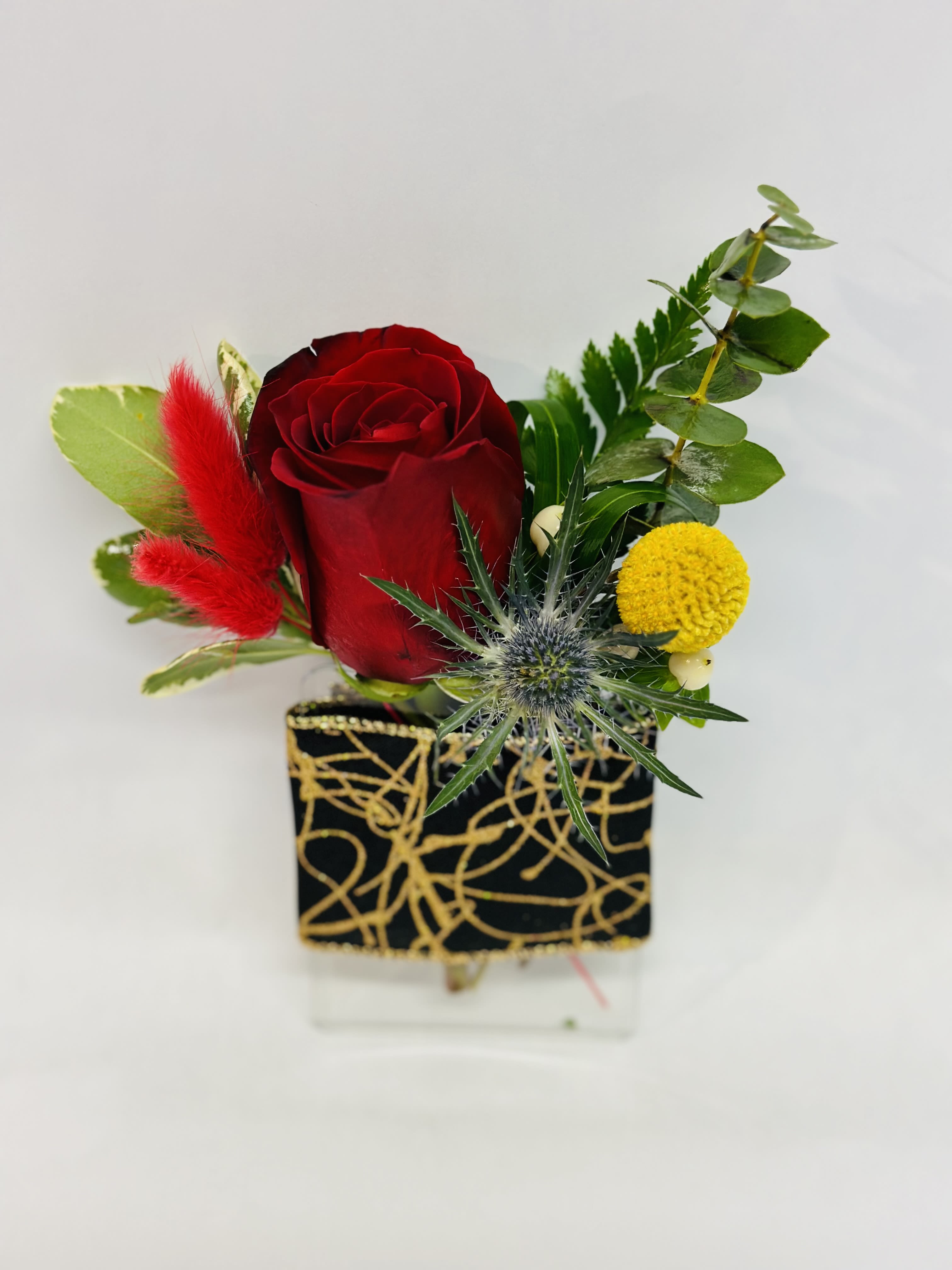 Red rose arrangement in a black and gold square vase