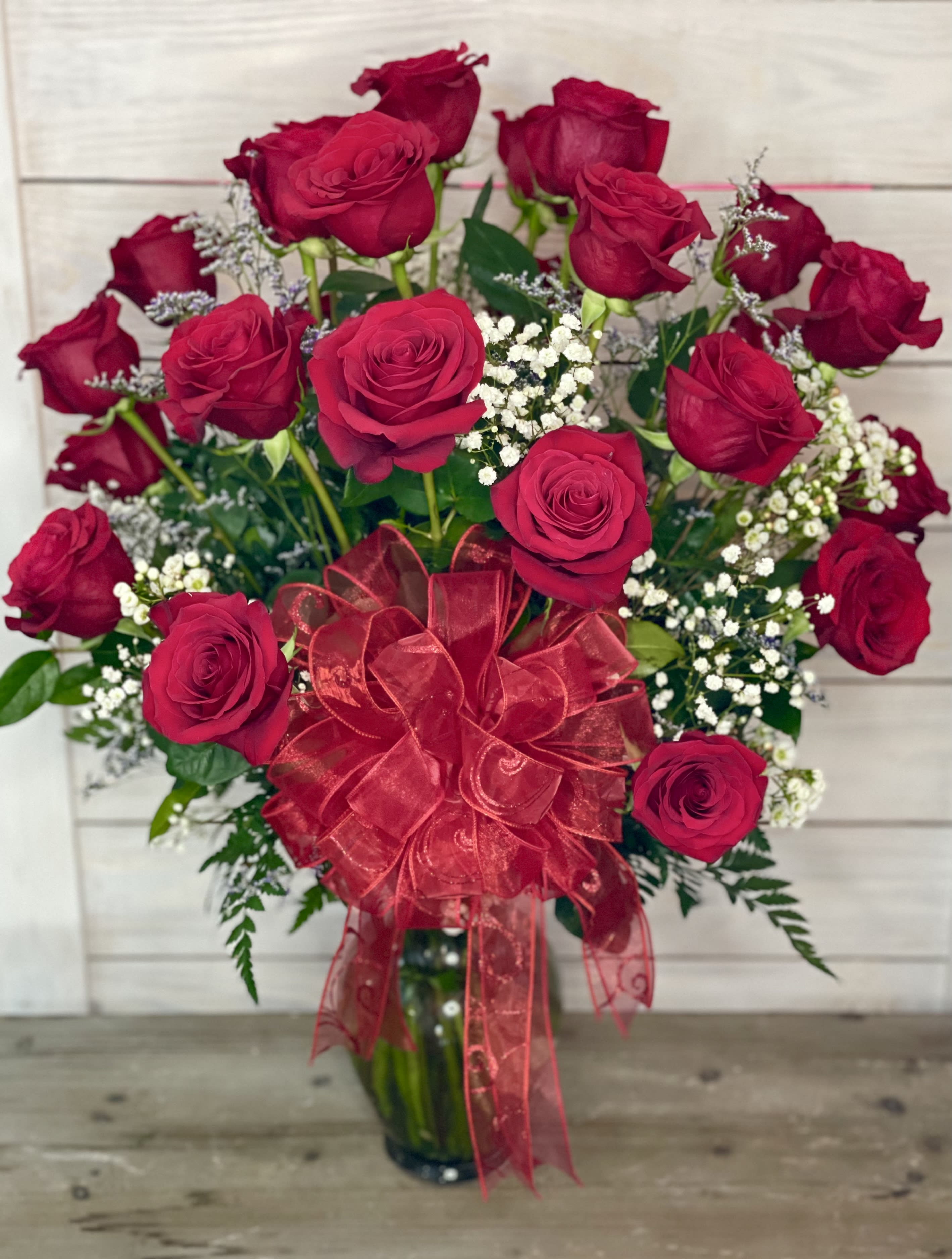 Bouquet of red roses with baby's breath and a red ribbon in a glass vase