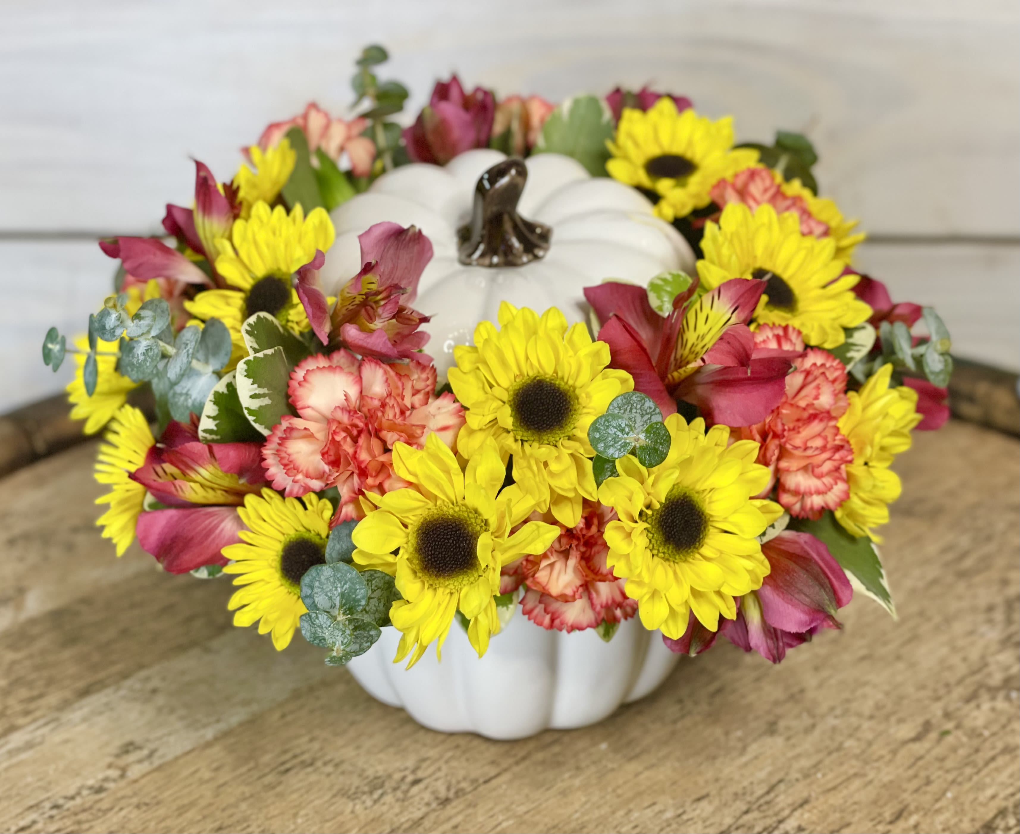 Sunflower and pink flower arrangement in a white pumpkin container