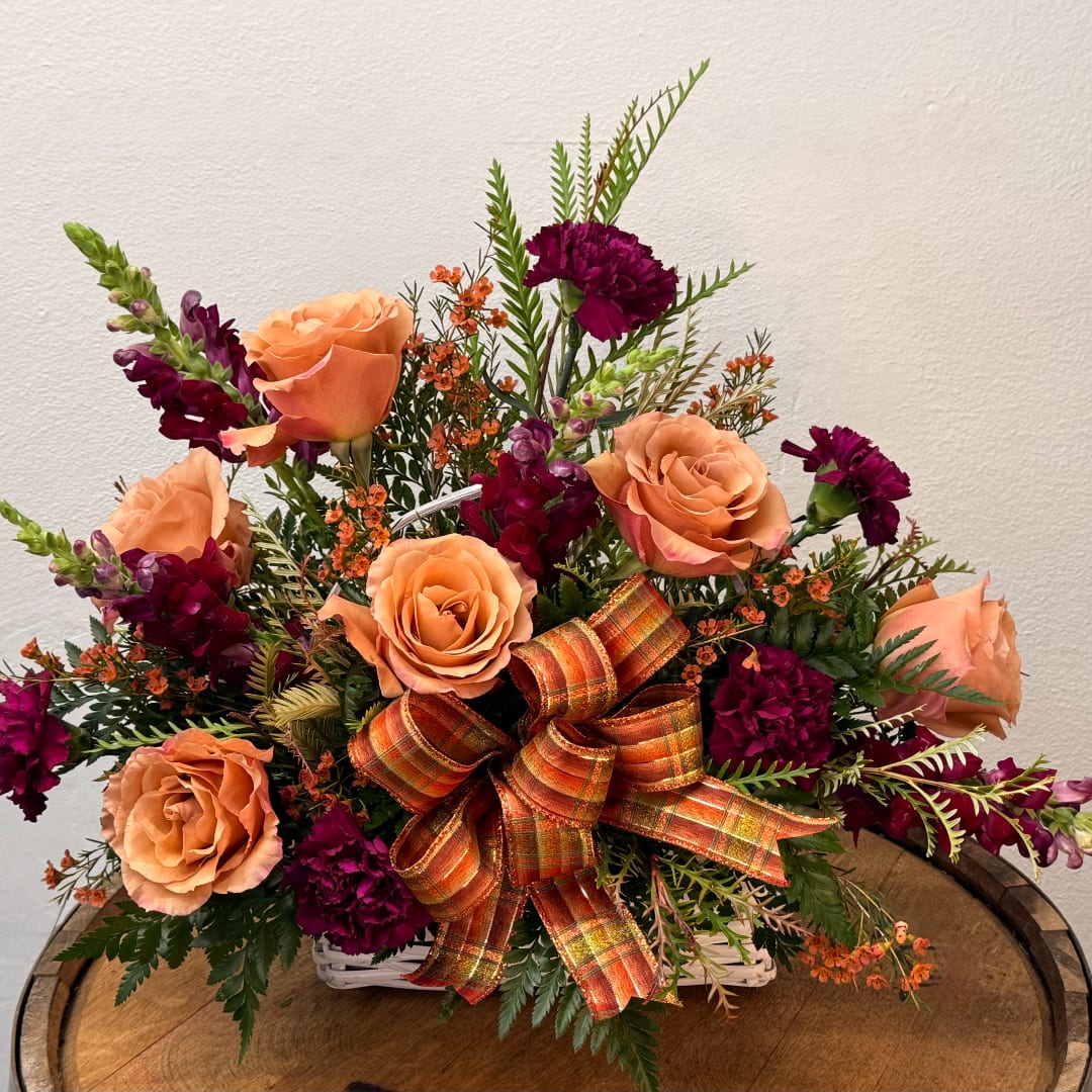 Peach roses and deep purple carnations in a white basket with a plaid bow
