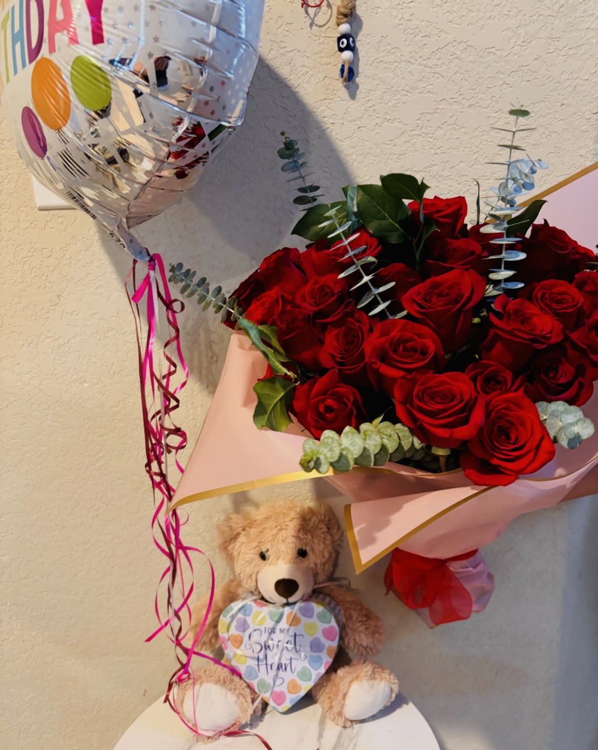 Luxury Red Rose Bouquet with Teddy Bear &amp; Birthday Balloon - A beautiful romantic flower arrangement in San Antonio featuring fresh red roses wrapped in elegant premium paper with eucalyptus greenery, paired with a birthday balloon and a cute teddy bear for a complete gift experience. Handcrafted by Snyder Flowers San Antonio, this luxury floral gift set is perfect for birthdays, anniversaries, romantic surprises, Valentine’s Day, or special celebrations.   A perfect combination of flowers, balloon, and teddy bear to create a memorable and emotional gift.  We proudly offer same-day flower delivery in San Antonio with fresh premium roses and exceptional customer service.  Elegant floral gifts designed to impress with high-quality flowers and beautiful presentation.  Serving Stone Oak, Medical Center, Alamo Heights, Cibolo, Universal City, Live Oak, Helotes, Castle Hills, Shavano Park, and Downtown San Antonio.  Looking for a trusted florist in San Antonio, same day rose delivery, or romantic flower gifts near you? Snyder Flowers creates luxury floral arrangements and gift sets delivered fresh and ready to surprise.