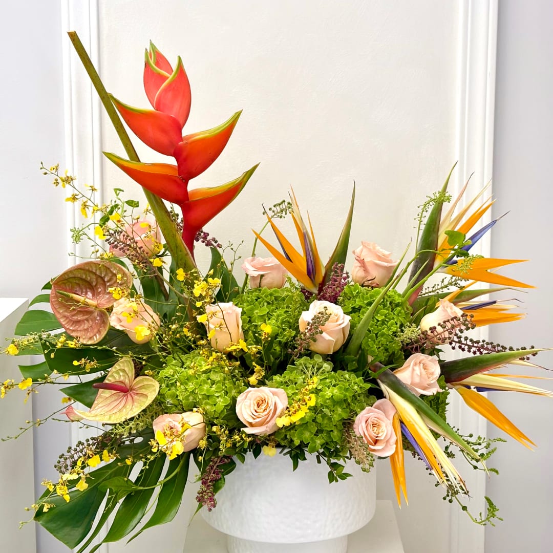 Tropical floral arrangement with pink roses and bird of paradise in a white vase