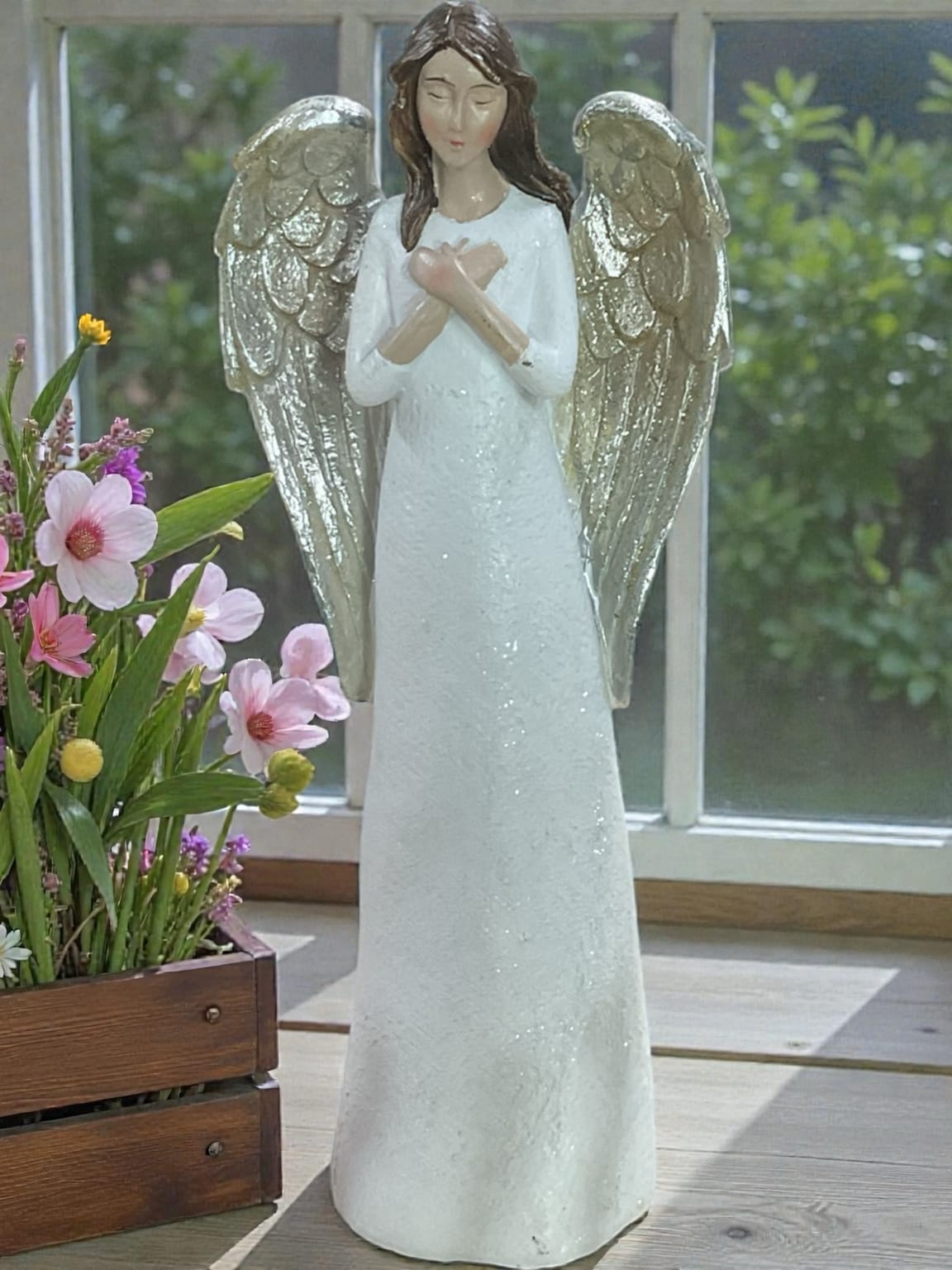 10” With All My Heart Angel Figurine - With All My Heart Angel Figurine is a beautiful keepsake that celebrates love, faith, comfort, and meaningful connections. Featuring graceful wings, a peaceful expression, and hands gently crossed over the heart, this 10 inch elegant figurine serves as a lasting reminder of the people, memories, and blessings we hold closest.  Its timeless design complements a variety of decorating styles and looks beautiful displayed on a mantel, bookshelf, bedside table, desk, entry table, or special display shelf. The neutral color palette and classic styling make it suitable for year-round display in both traditional and contemporary homes.  The Standard version includes the angel figurine accented with a coordinating ribbon. Deluxe and Premium versions pair the figurine with fresh flowers selected to complement its soft colors and peaceful appearance. Premium designs feature additional blooms and enhanced texture for greater visual impact while maintaining an elegant presentation.  A thoughtful gift for birthdays, Mother’s Day, encouragement, faith-based occasions, church members, caregivers, teachers, family, and friends, this angel offers a beautiful expression of love, appreciation, hope, and support. It is also an appropriate keepsake for remembrance, sympathy, memorial occasions, and honoring the memory of someone held close to the heart.