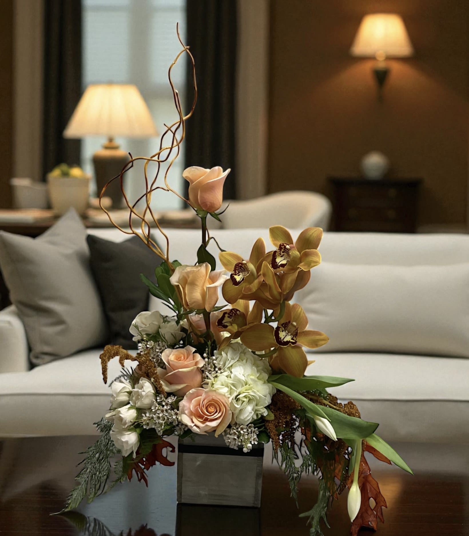 SPECIAL ORDER The Bourbon Collection - There is a reason some things get better with age.  A rare bottle saved for a special occasion. The worn leather chair everyone gravitates toward. The stories that get better every time they’re told. The Bourbon Collection was inspired by those moments—the ones that can’t be rushed and shouldn’t be forgotten.  This isn’t simply a flower arrangement. It’s a feeling. A mood. A statement. Designed with rich textures, warm tones, and dramatic lines, The Bourbon Collection brings the same sense of character, confidence, and quiet sophistication found in the world’s finest bourbons.  Whether you’re celebrating a birthday, congratulating a colleague, thanking a client, recognizing an achievement, sending Father’s Day flowers, or surprising someone who appreciates timeless style, this design creates an unforgettable first impression. It’s bold without being loud, refined without being formal, and distinctive without trying too hard.  The Standard version offers a beautiful expression of warmth, character, and elegance. The Deluxe version includes additional blooms for greater fullness, texture, and visual impact. The Premium version features even more flowers and premium accents, creating a lush, luxurious presentation designed to command attention from every angle.  Because some gifts are opened, admired, and forgotten. The Bourbon Collection was designed to be remembered.  Flowers may vary; the overall style, color palette, and value will be maintained. 