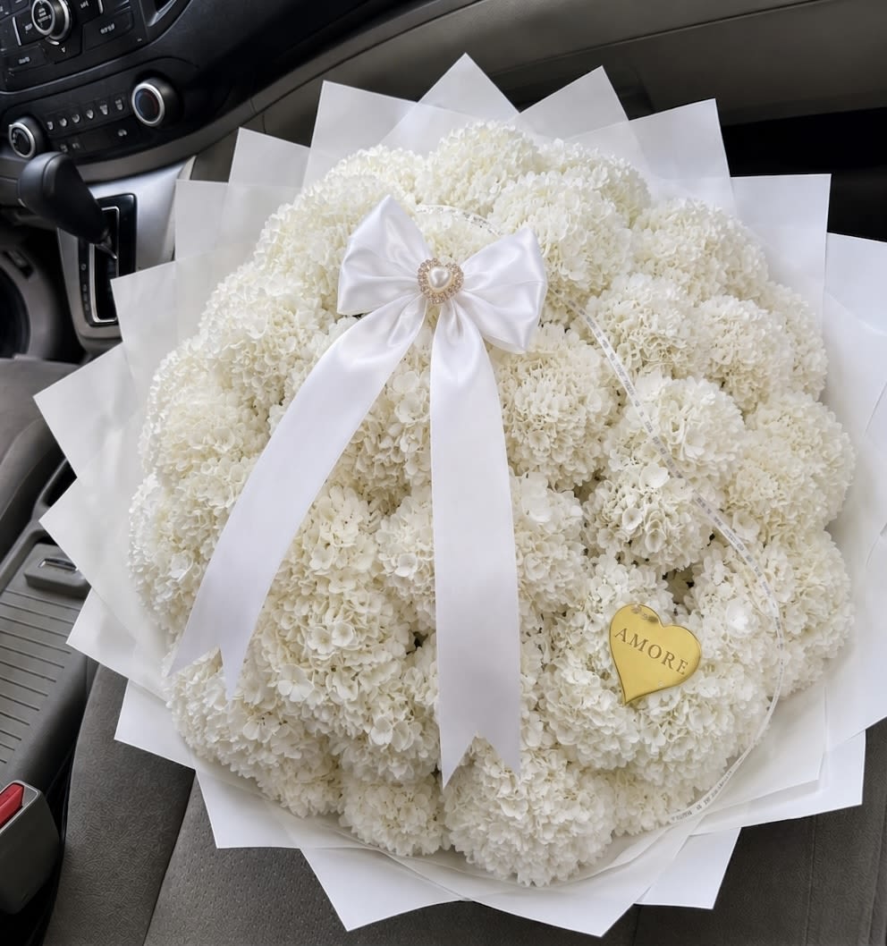     Hydrangea Luxury Bouquet - Our Hydrangea Luxury Bouquet is a timeless arrangement designed to bring elegance, softness, and sophistication to any special occasion. Featuring lush premium hydrangeas carefully arranged in a full, cloud-like shape, this bouquet is wrapped in elegant luxury paper for a refined and modern presentation.  Inspired by minimalist luxury aesthetics, this arrangement is perfect for anniversaries, birthdays, celebrations, sympathy gestures, romantic moments, or meaningful gifts where beauty speaks for itself.  Available in multiple sizes: • 5 Hydrangeas • 10 Hydrangeas • 15 Hydrangeas  Hydrangea colors may vary depending on season and store availability. Customers are welcome to request preferred colors whenever possible.  For an even more personalized touch, satin ribbons with custom messages such as “Happy Anniversary,” “Happy Birthday,” or short custom phrases can be added upon request.  Please note: Hydrangeas are natural flowers and each bloom may vary slightly in shape, tone, and fullness while maintaining the same elegant overall aesthetic.
