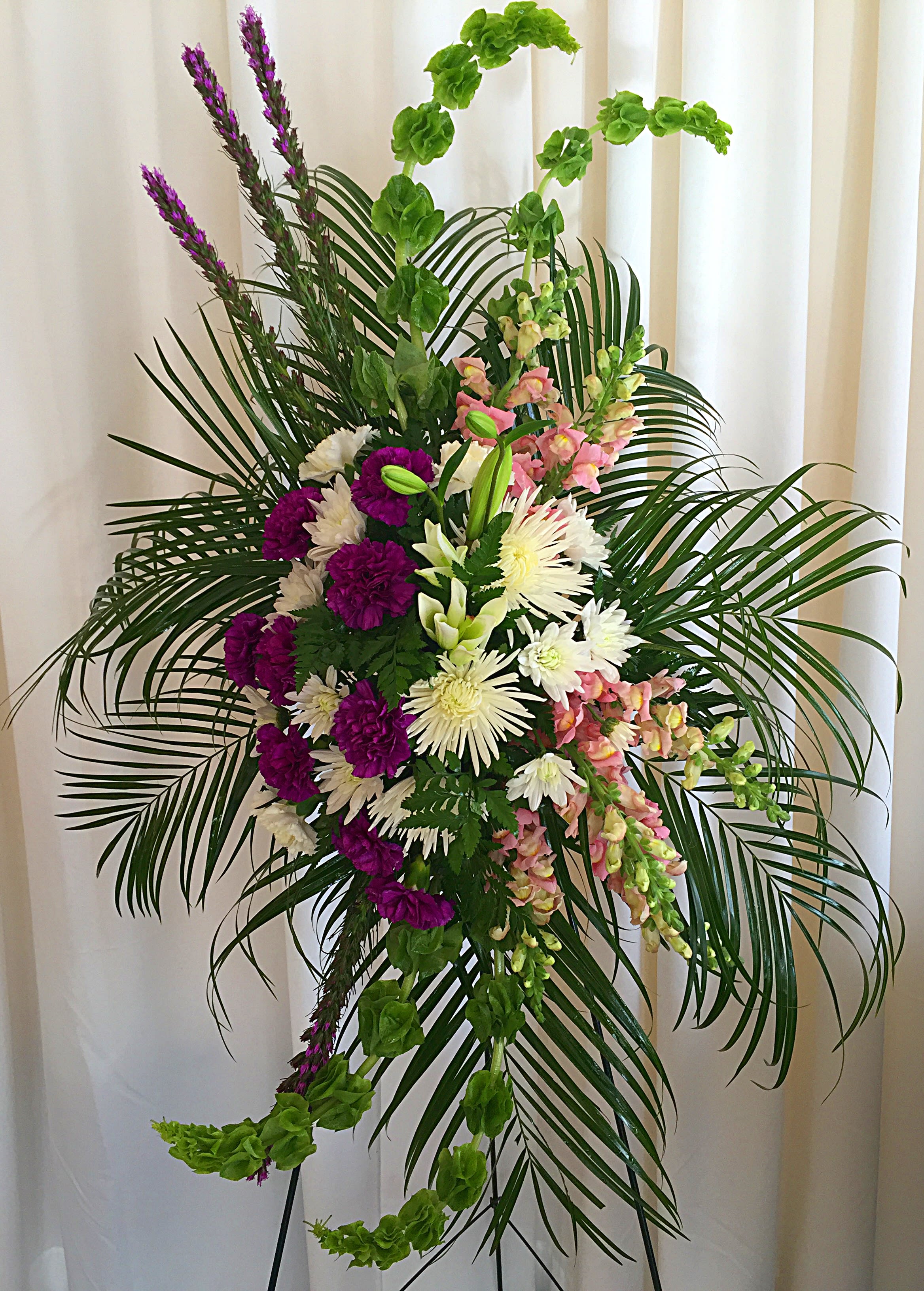Tall floral spray with purple, white, and pink blooms and palm fronds