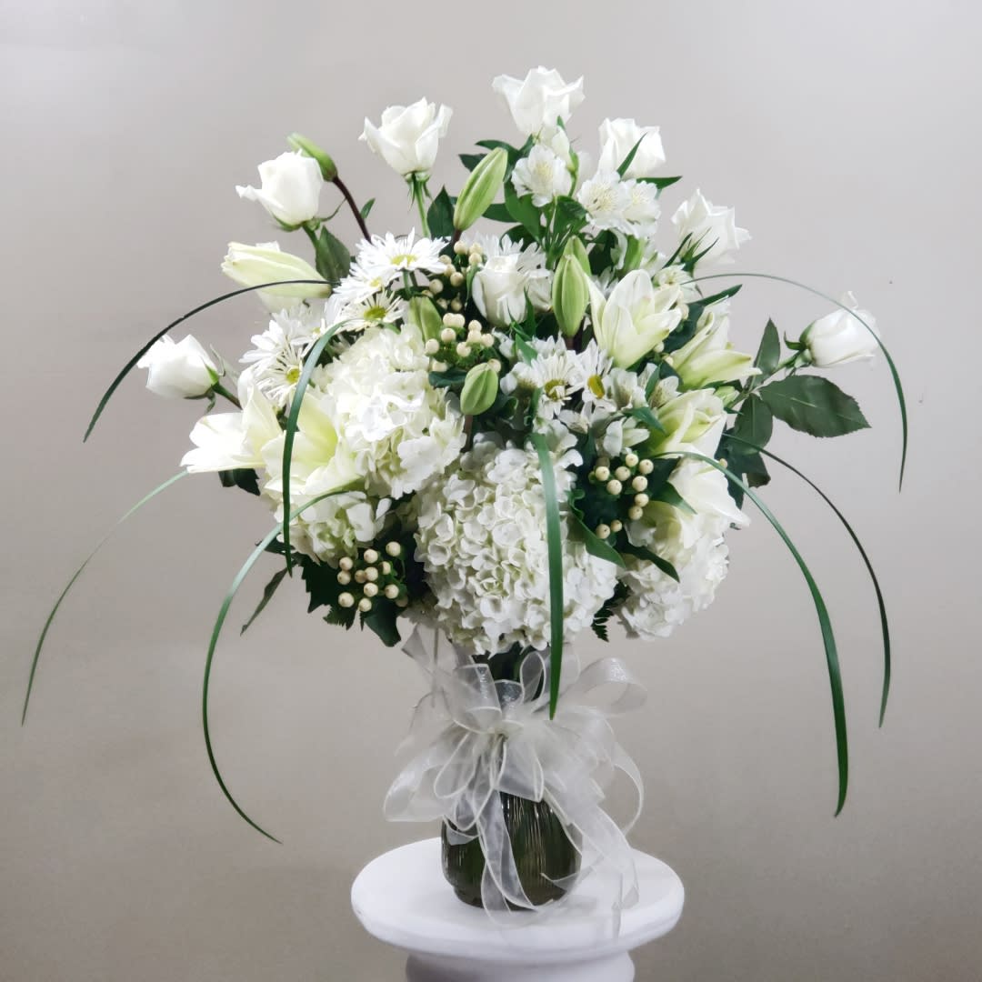 White floral bouquet in a glass vase with a sheer ribbon bow