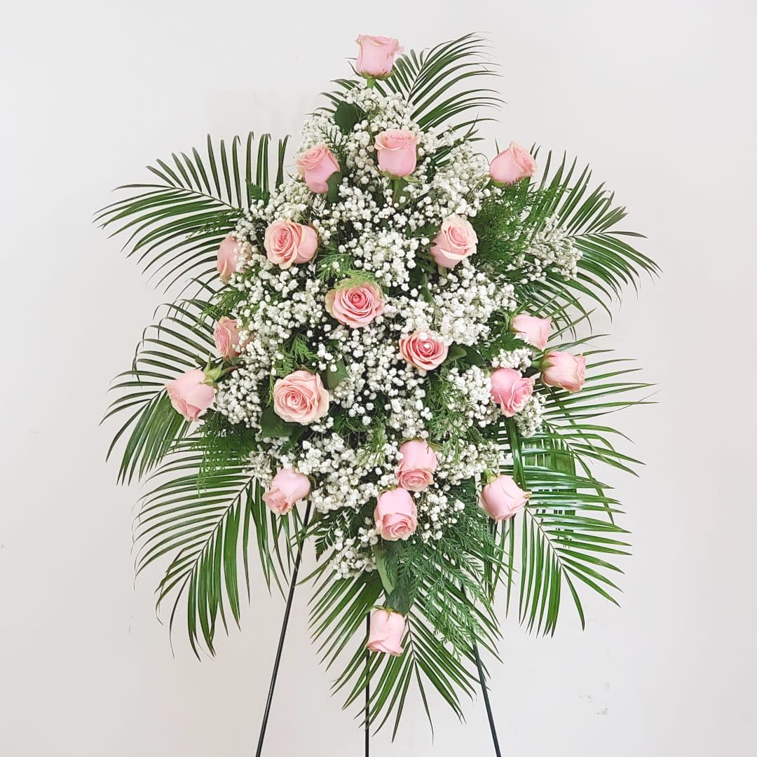 Pink roses and white baby's breath on a standing spray with palm fronds