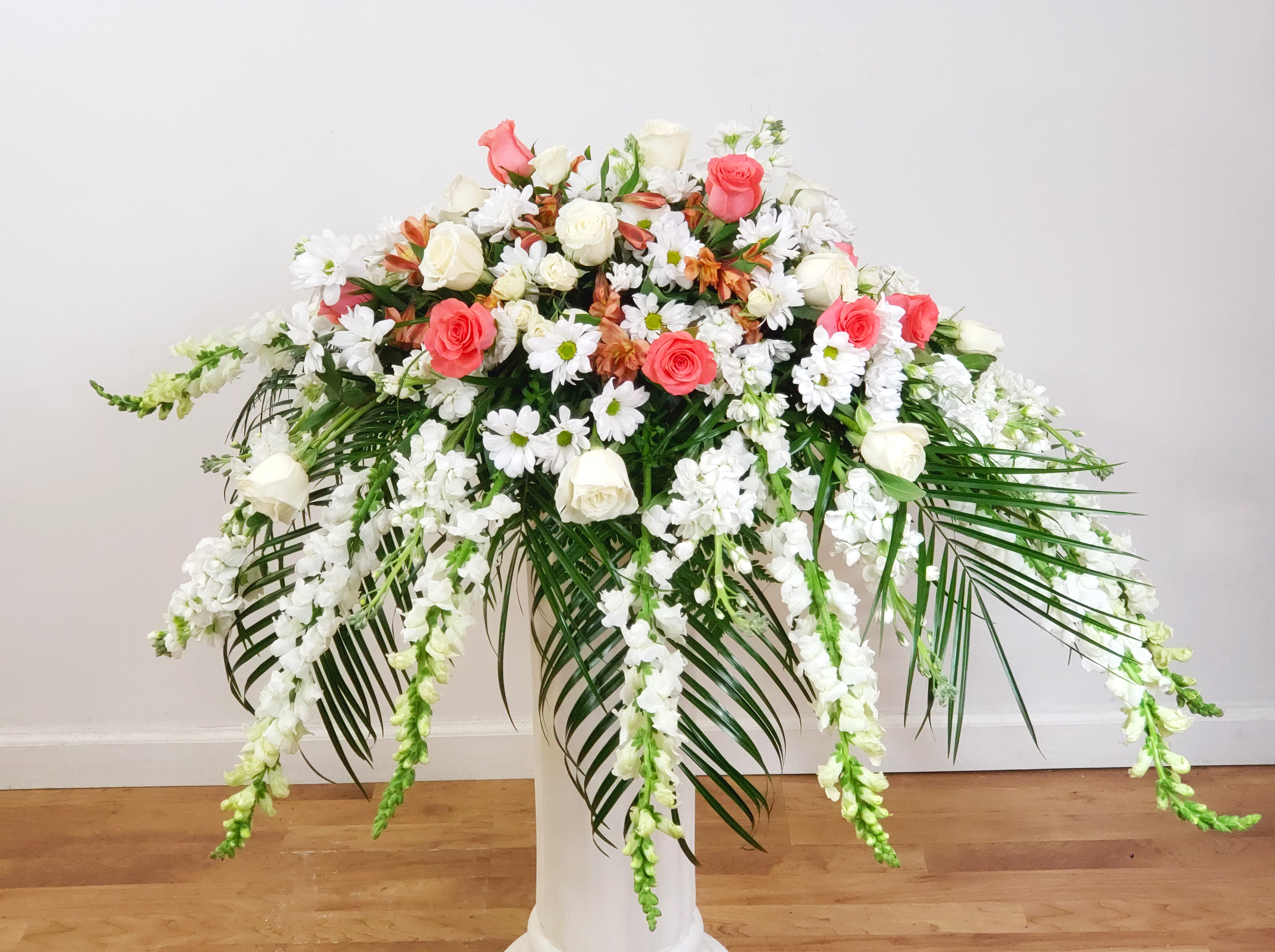 Large floral arrangement of pink and white roses with cascading white blooms