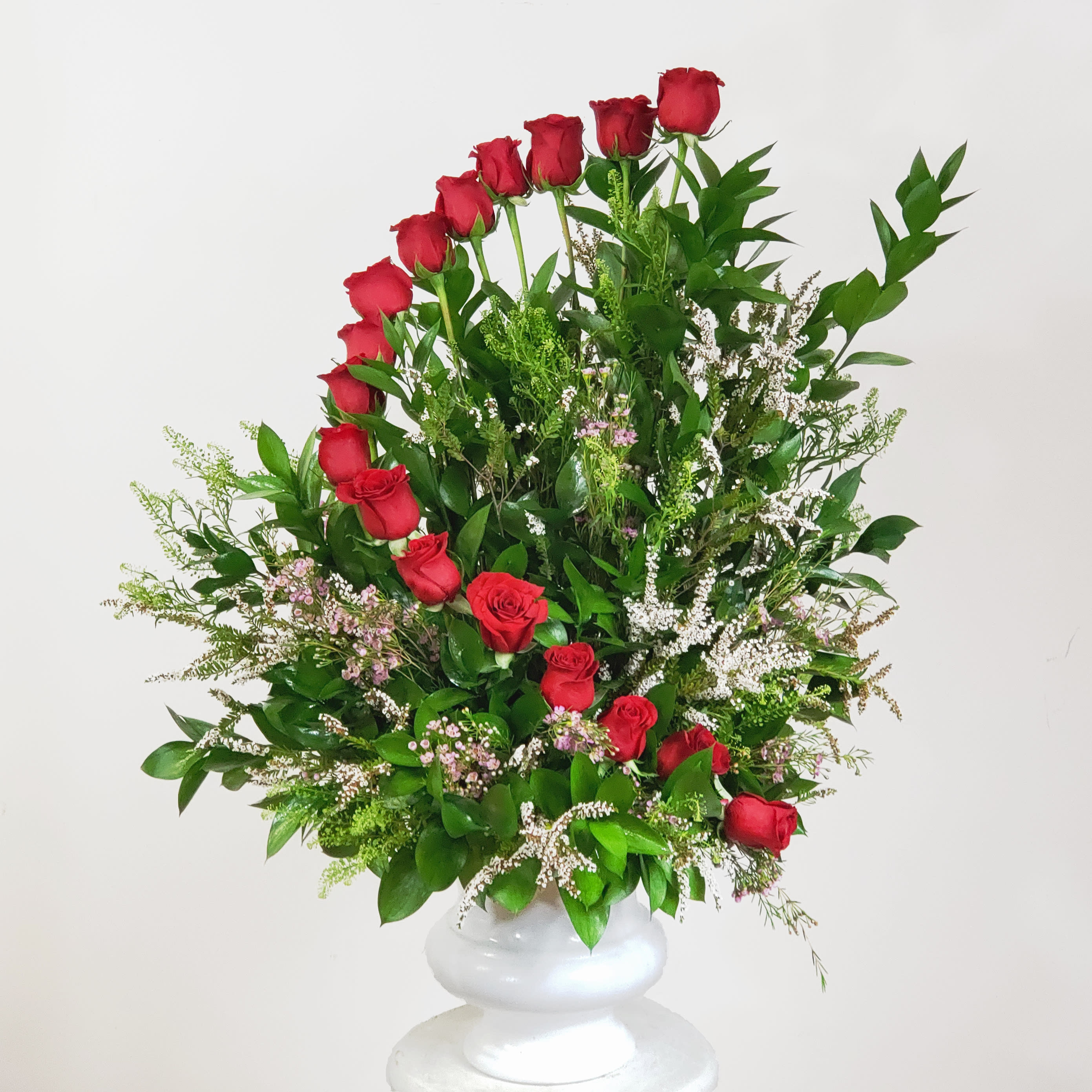 Tall arrangement of red roses in a white vase