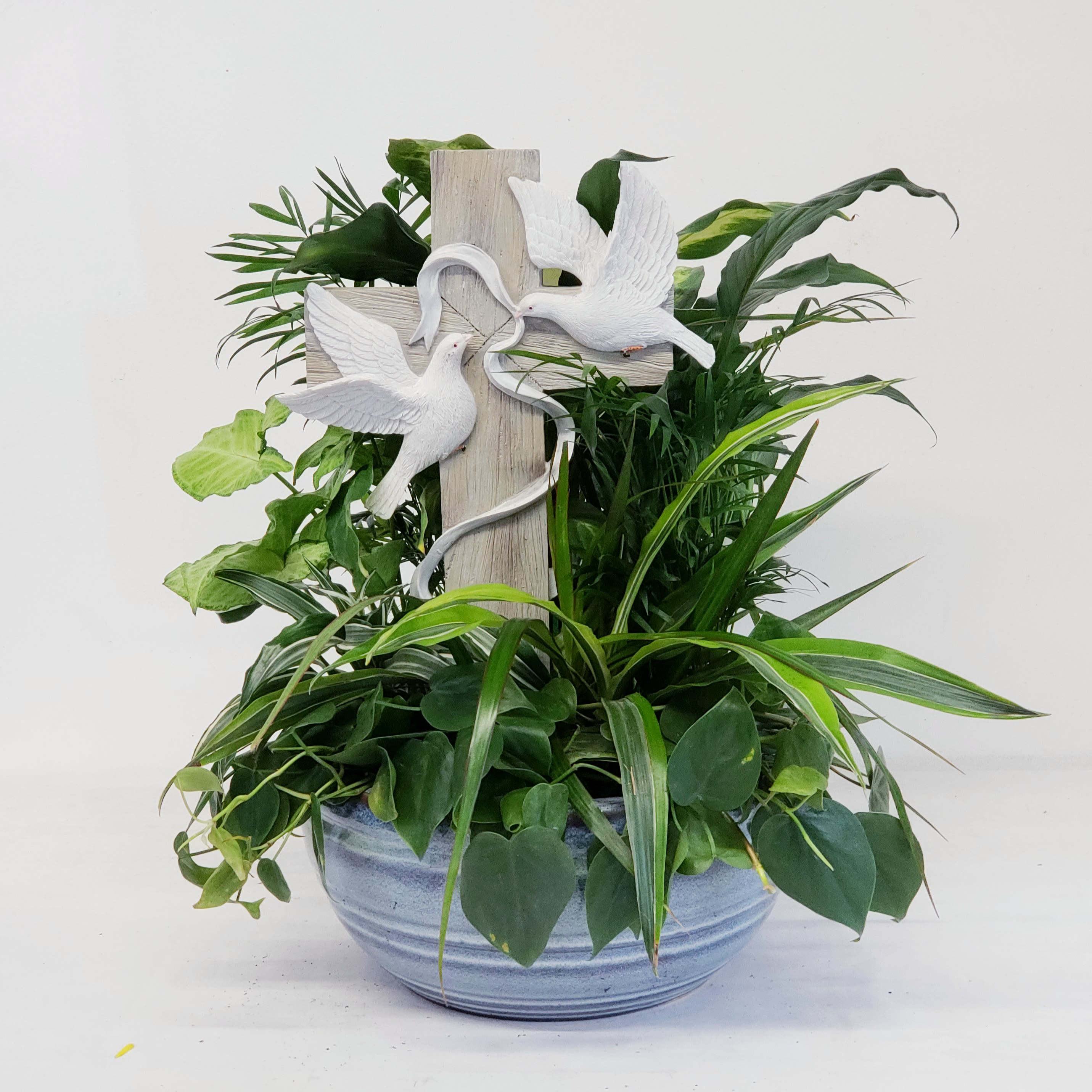 Potted green plant arrangement with a wooden cross and white doves